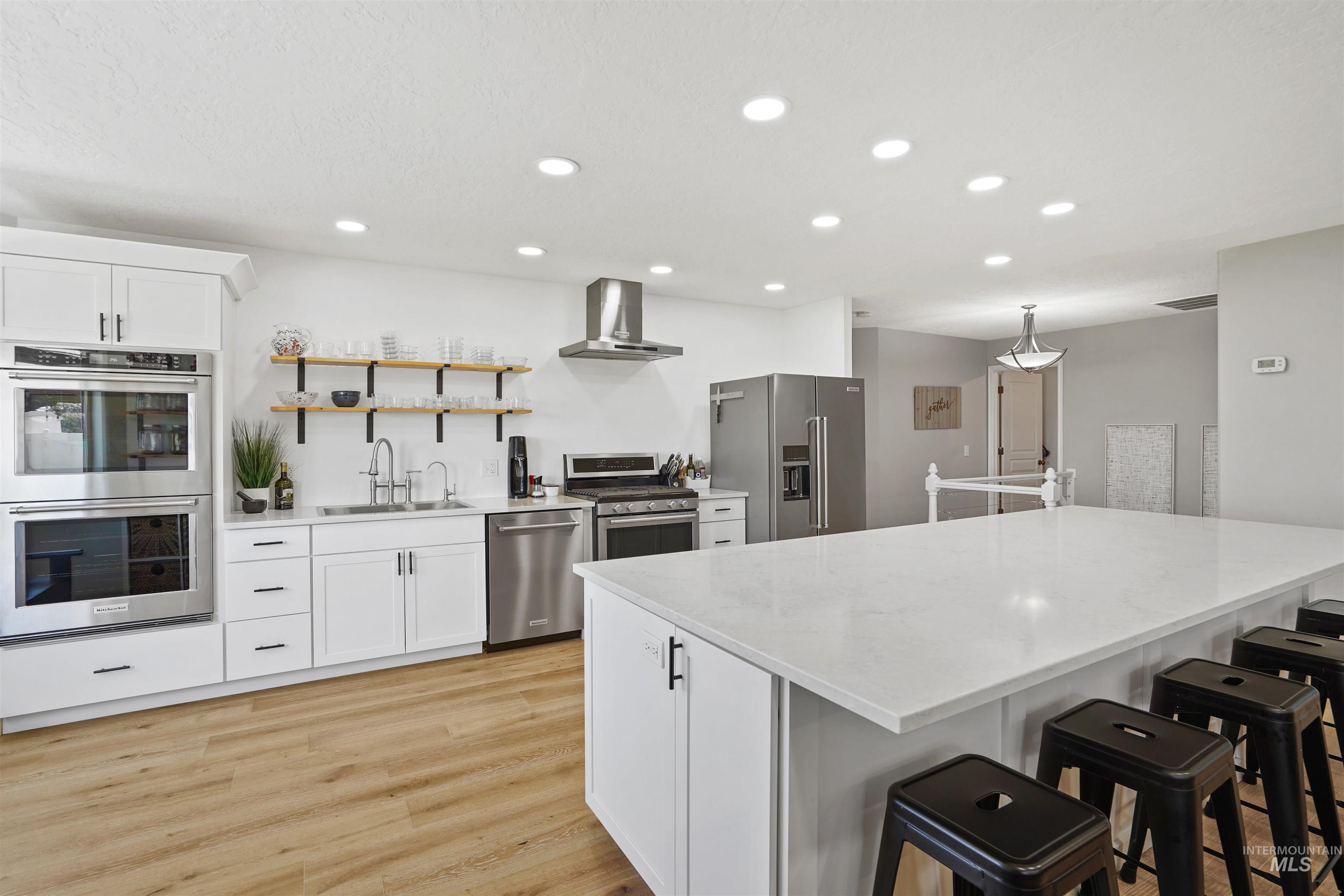 Kitchen featuring white cabinetry, open shelves, stainless steel appliances, a breakfast bar area, and recessed lighting