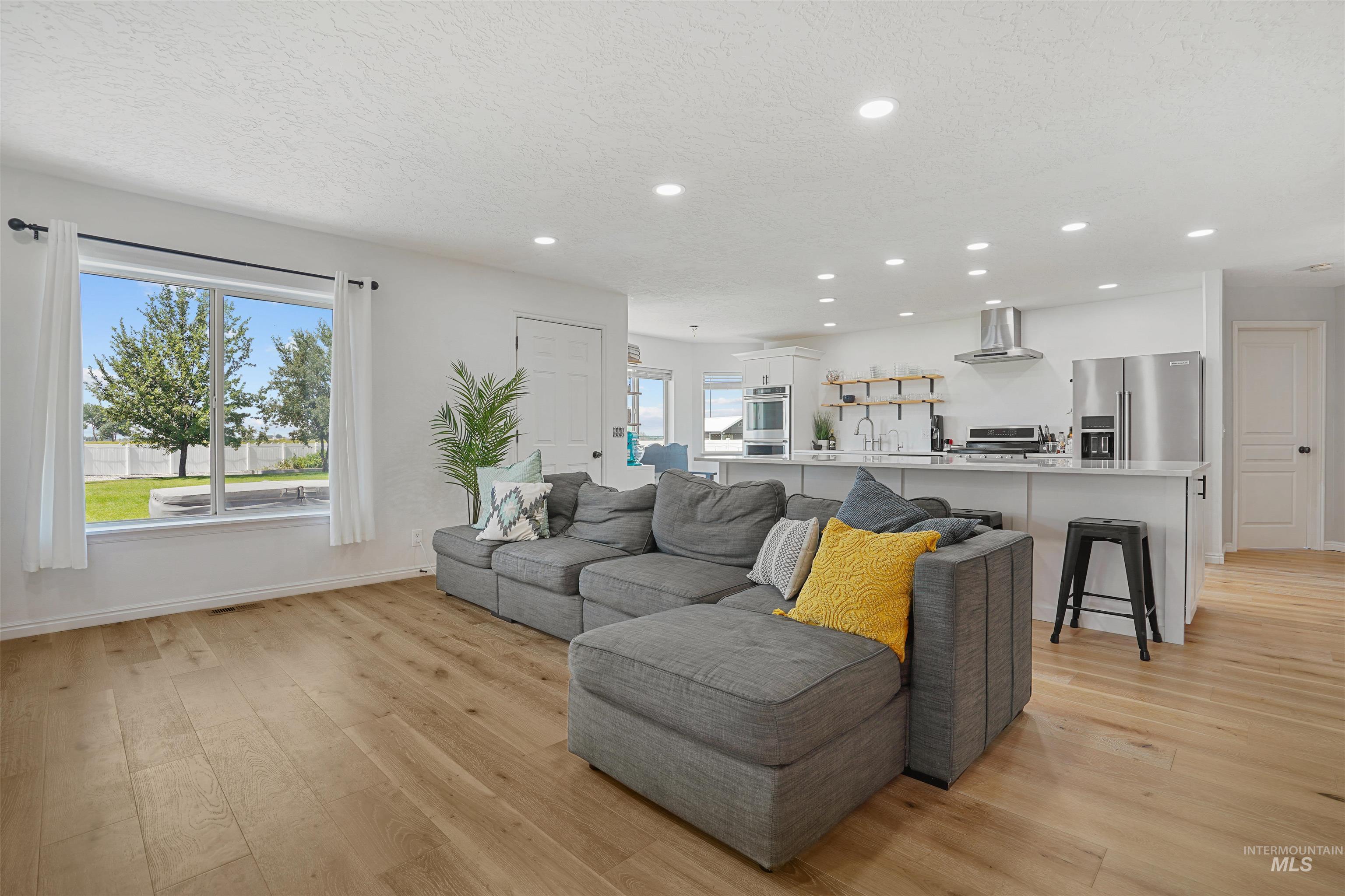 Living room featuring light wood finished floors, recessed lighting, and a textured ceiling