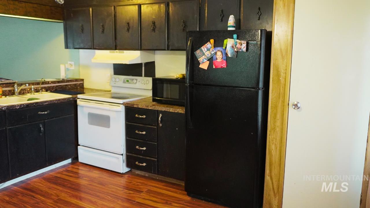 Kitchen with black appliances, dark wood-type flooring, and under cabinet range hood