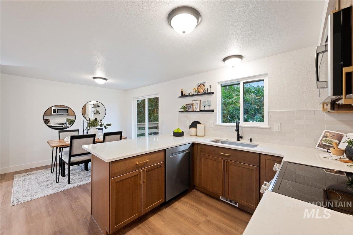 Kitchen featuring a peninsula, appliances with stainless steel finishes, light wood-type flooring, open shelves, and a textured ceiling
