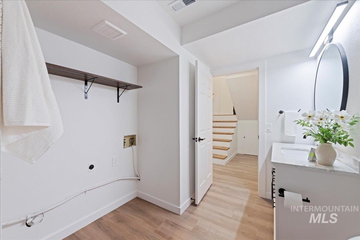 Laundry room with hookup for a washing machine, light wood-type flooring, and hookup for an electric dryer
