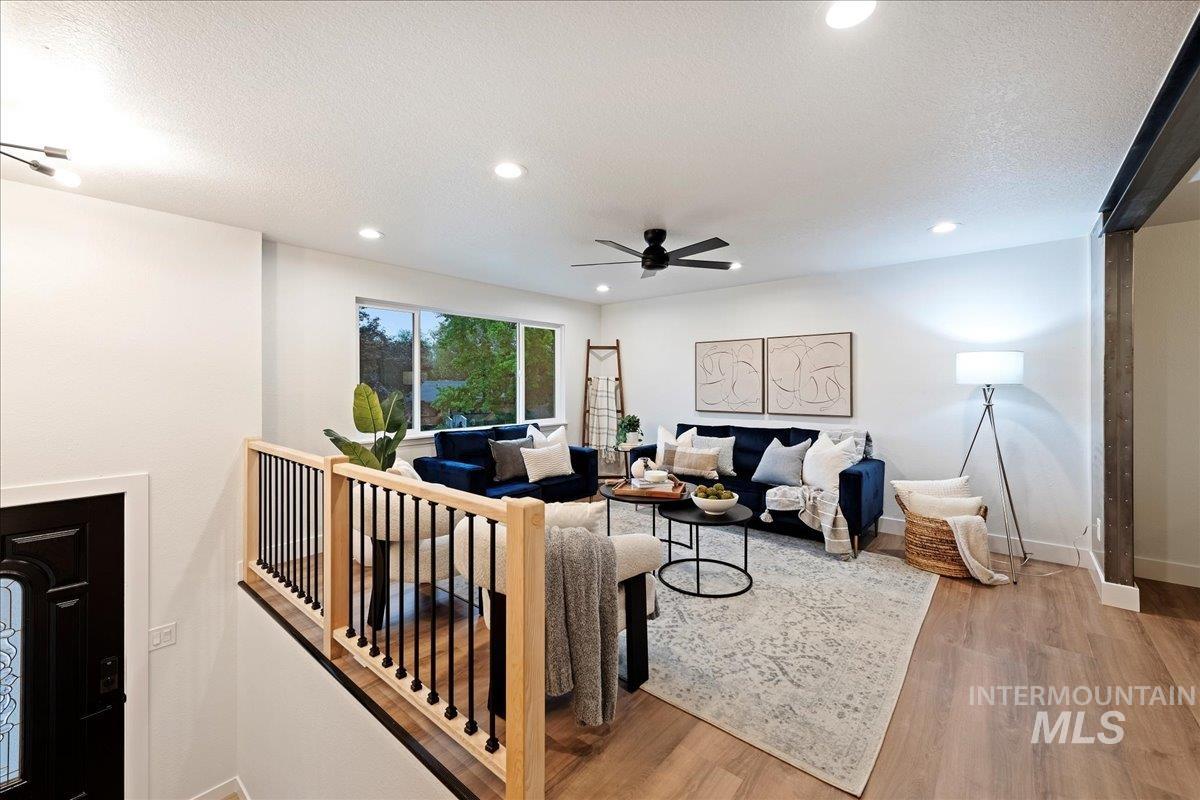 Living room featuring light wood-type flooring, a textured ceiling, ceiling fan, and recessed lighting