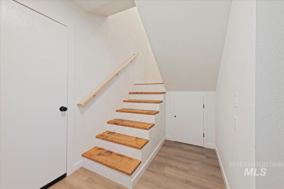 Stairway featuring wood finished floors and a textured wall