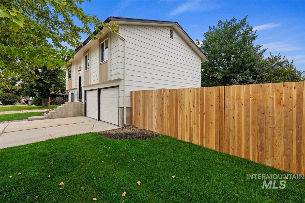 View of side of property featuring an attached garage and concrete driveway