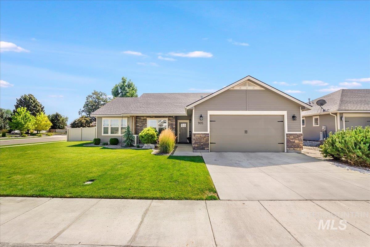 View of front of house featuring a garage, driveway, and a front lawn