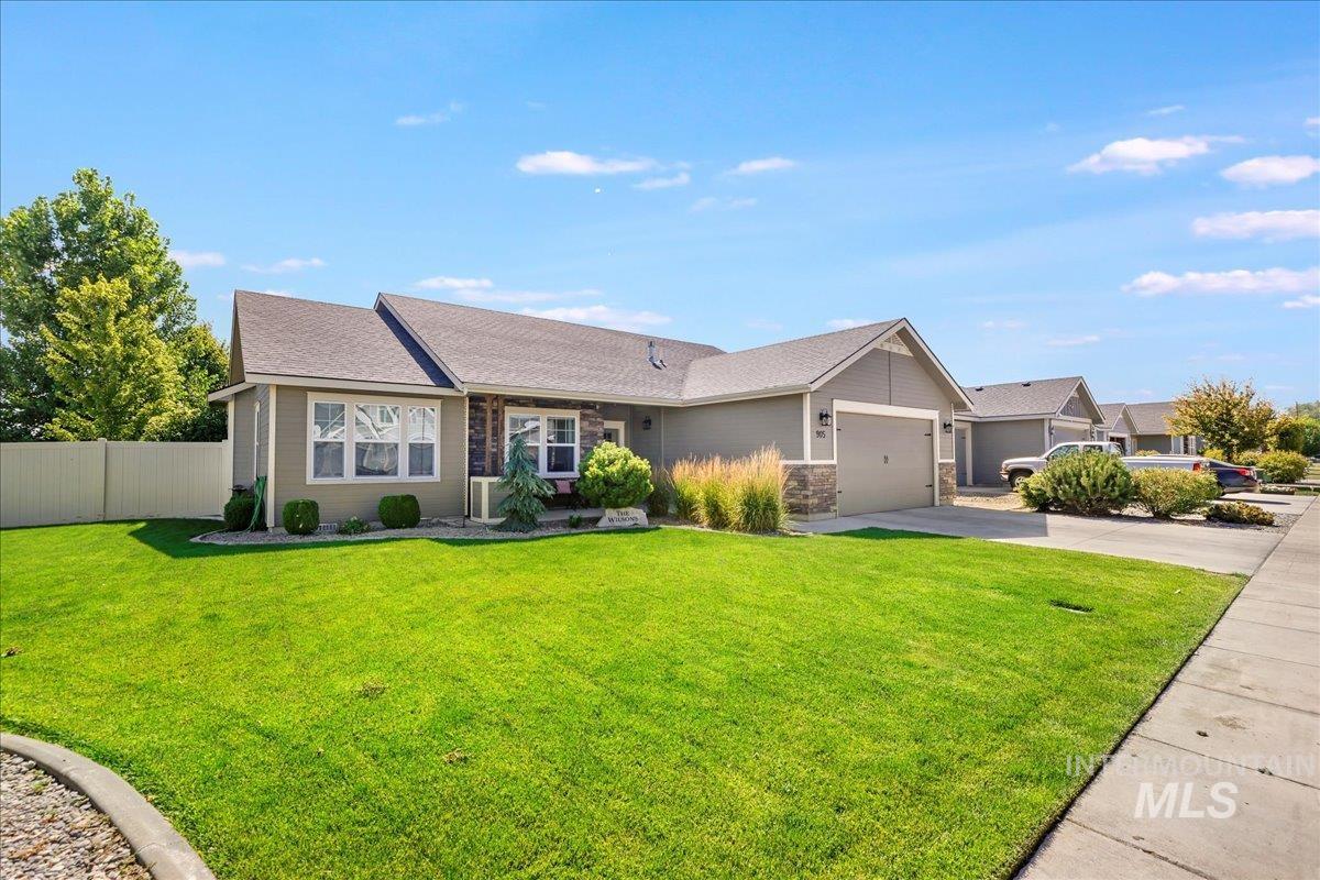 Single story home with concrete driveway, an attached garage, roof with shingles, and stone siding
