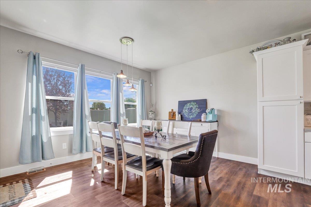 Dining space with dark wood-style floors and baseboards