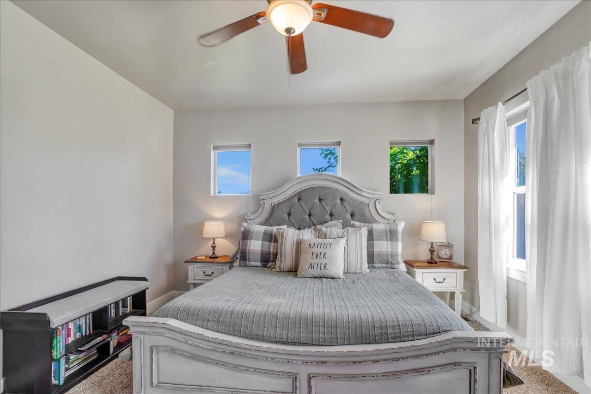 Carpeted bedroom with a ceiling fan and baseboards