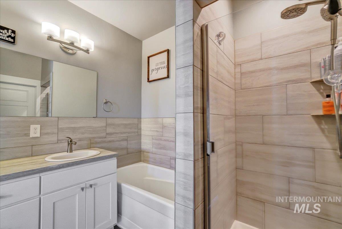 Full bathroom featuring vanity, a shower stall, and a garden tub