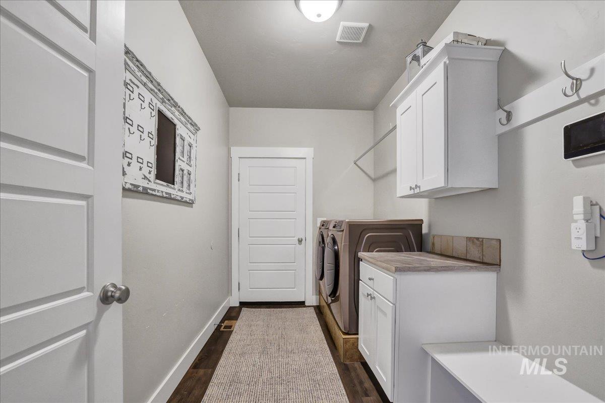 Laundry room with washer and clothes dryer, dark wood-style flooring, and cabinet space