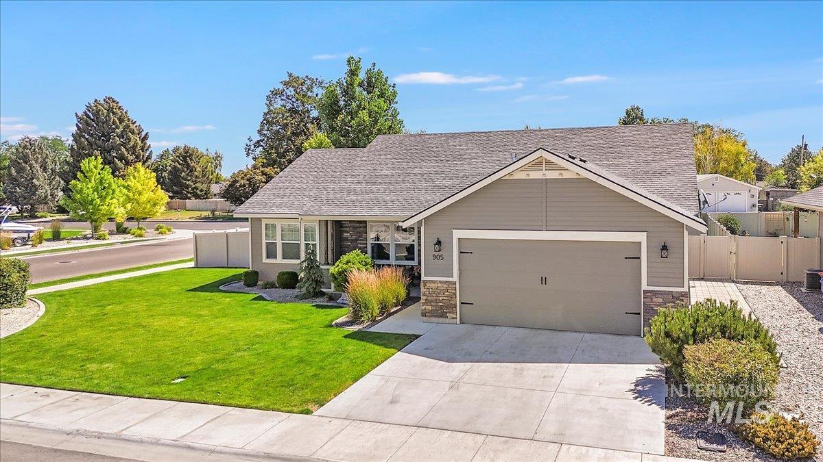View of front of property featuring concrete driveway, an attached garage, stone siding, and roof with shingles