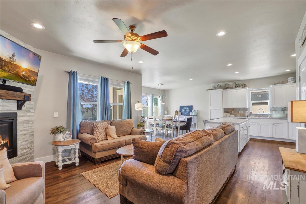 Living room featuring a ceiling fan, dark wood-style flooring, a fireplace, and recessed lighting