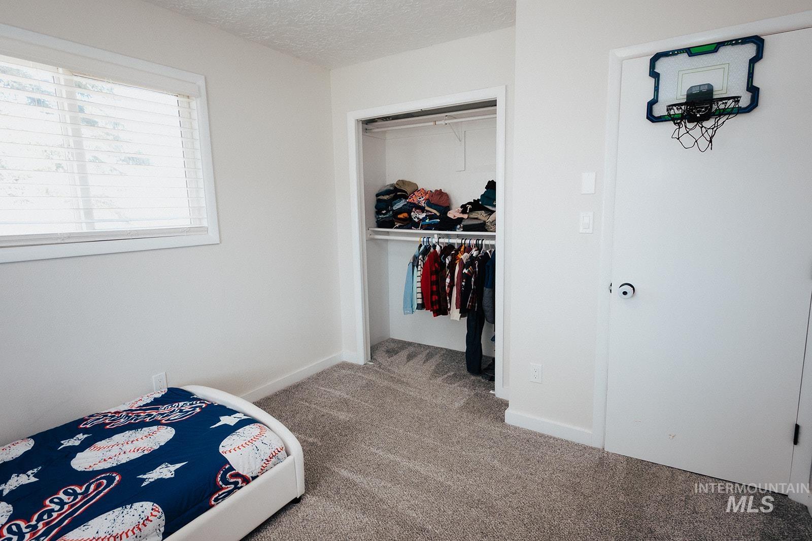 Bedroom featuring light carpet, a closet, and a textured ceiling