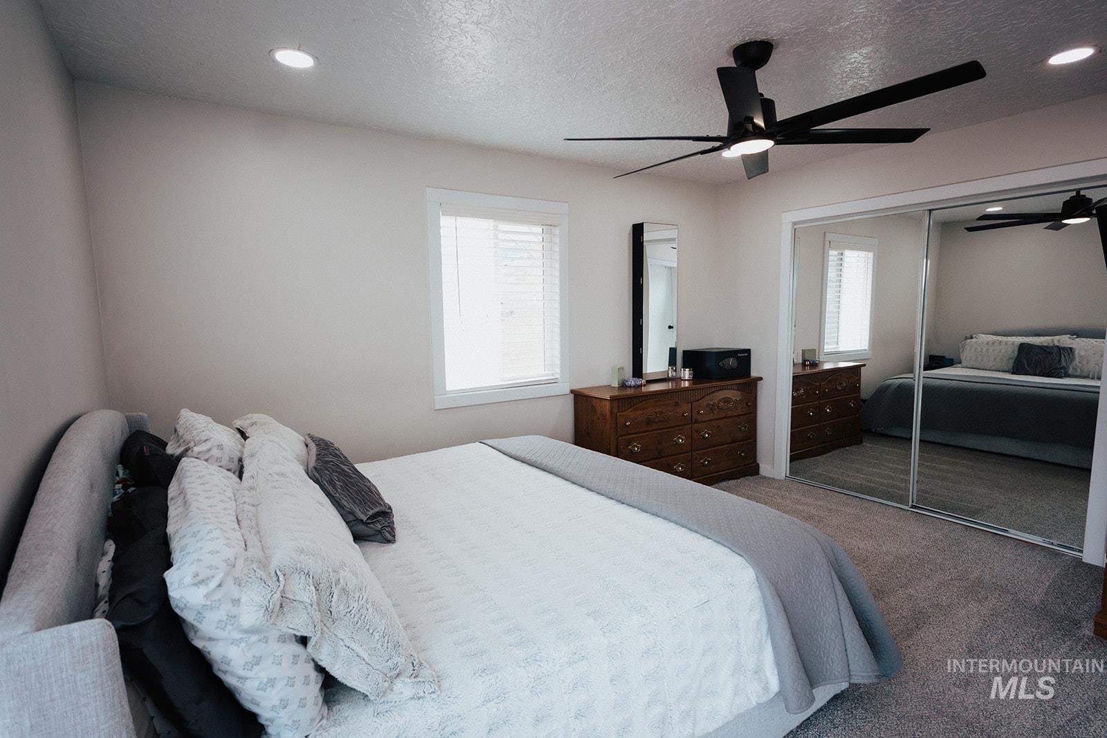 Carpeted bedroom with multiple windows, a textured ceiling, ceiling fan, a closet, and recessed lighting