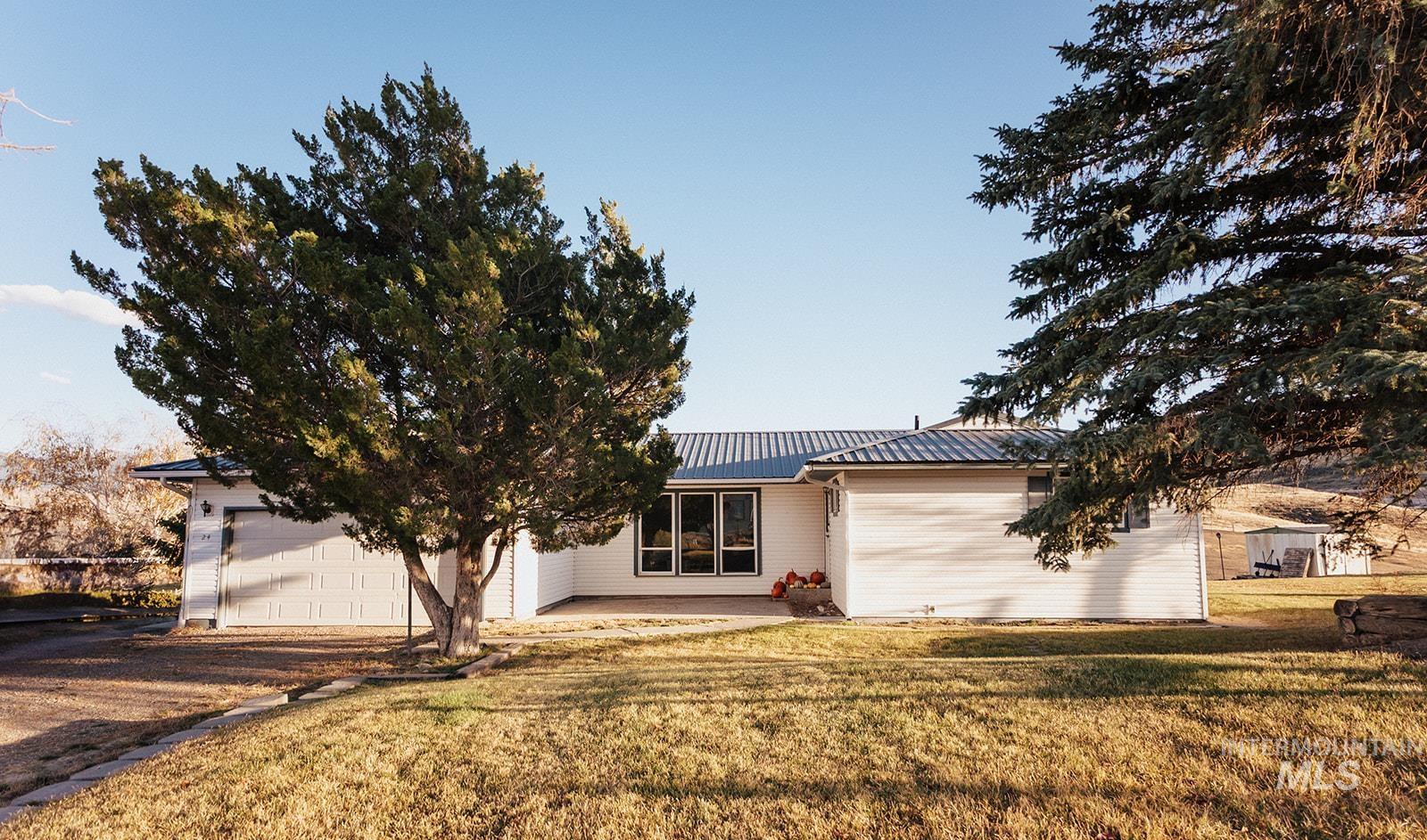 Ranch-style house with a metal roof, a front lawn, a patio area, and a garage