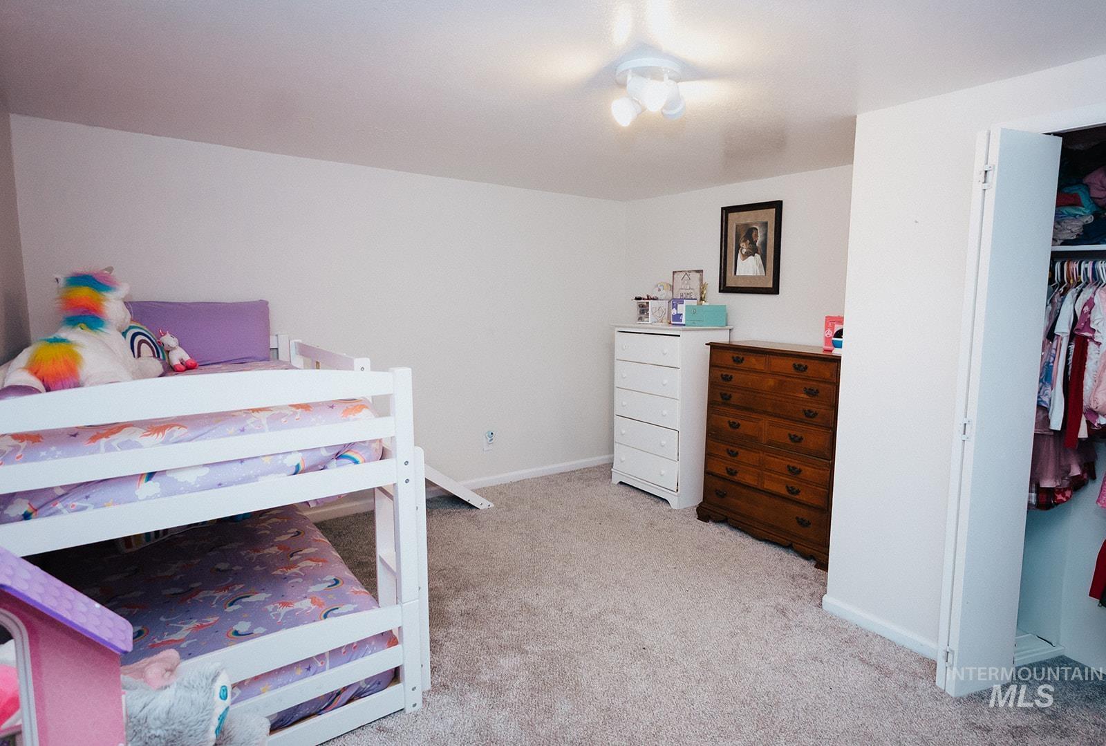 Basement Bedroom with light colored carpet and a closet
