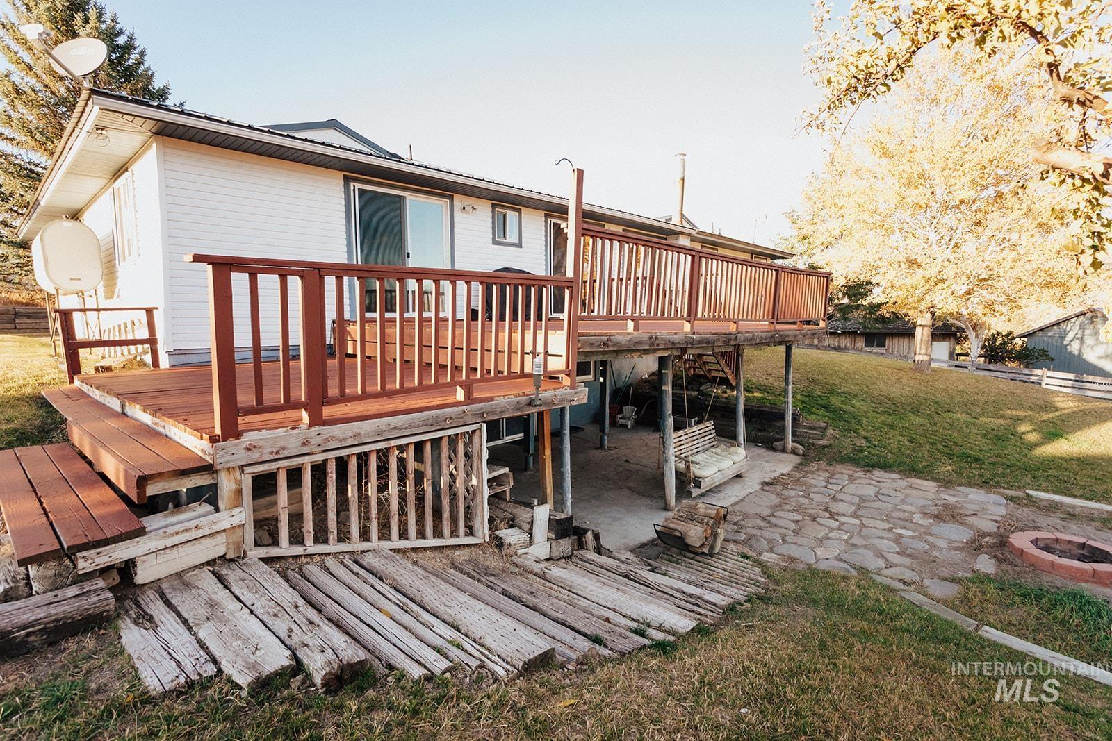 Back of property with a wooden deck, a lawn, a metal roof, and a patio area