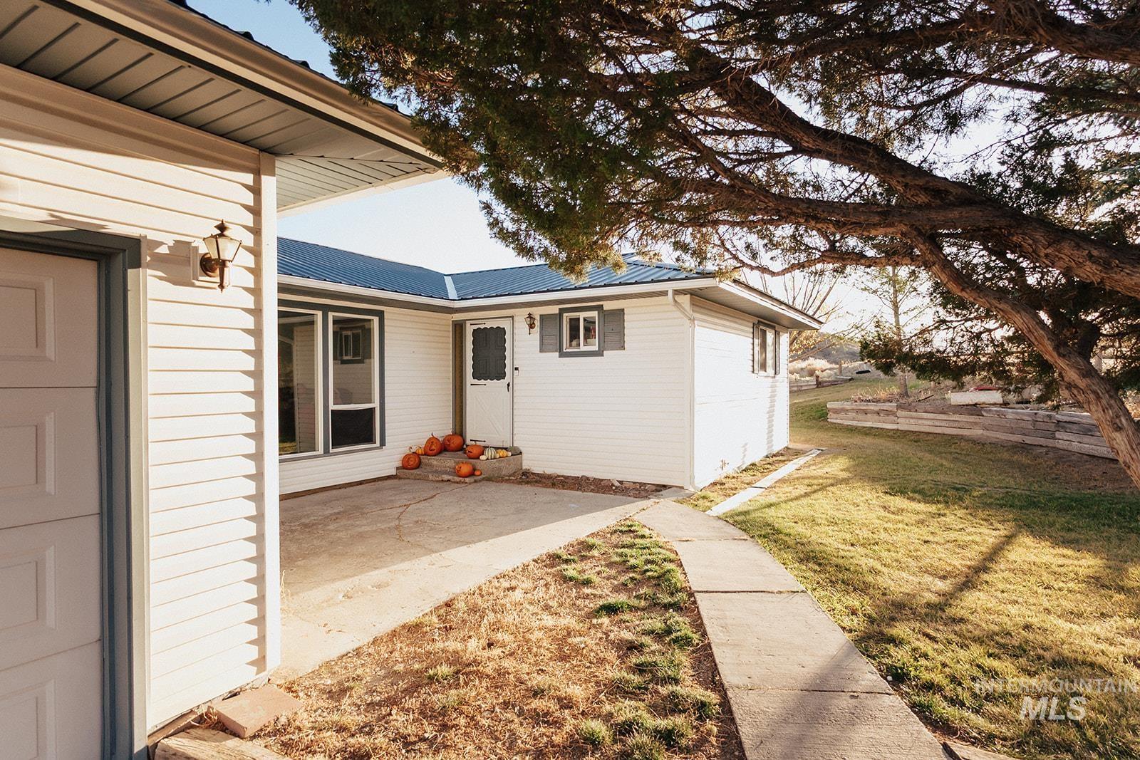 Doorway to property with a yard, a metal roof, and a patio