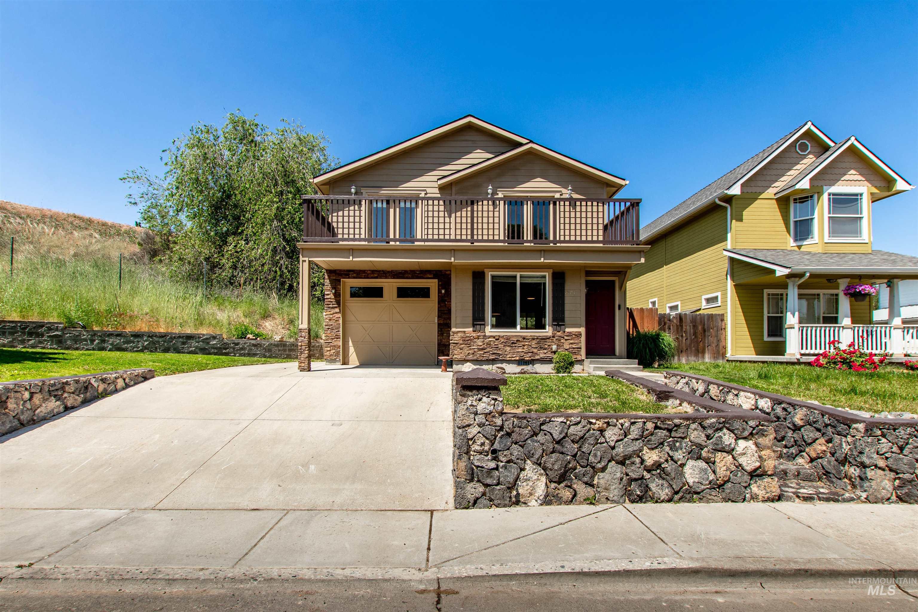 View of front facade featuring concrete driveway, an attached garage, stone siding, and covered porch