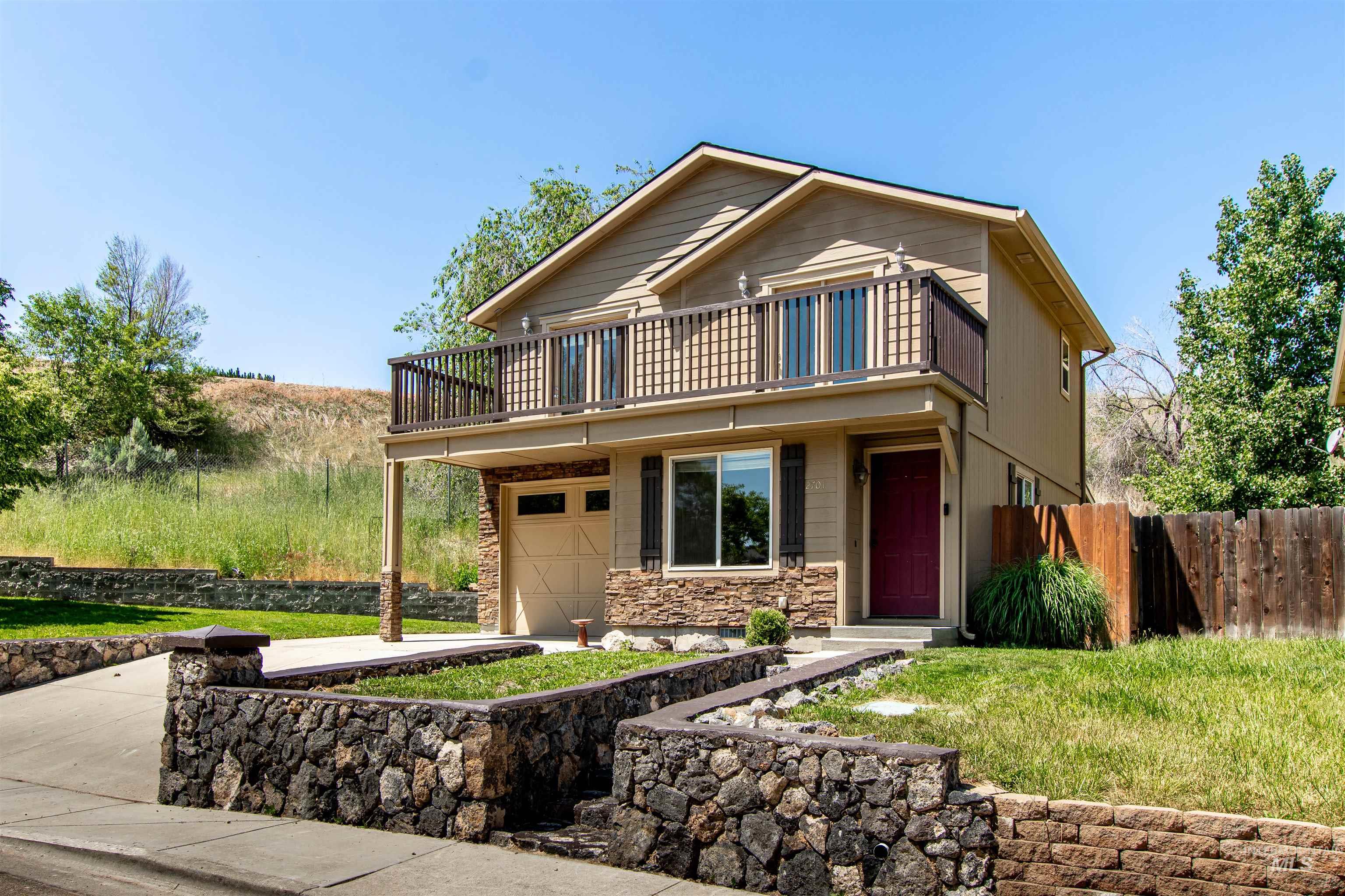 View of front of property with stone siding, an attached garage, and a front yard