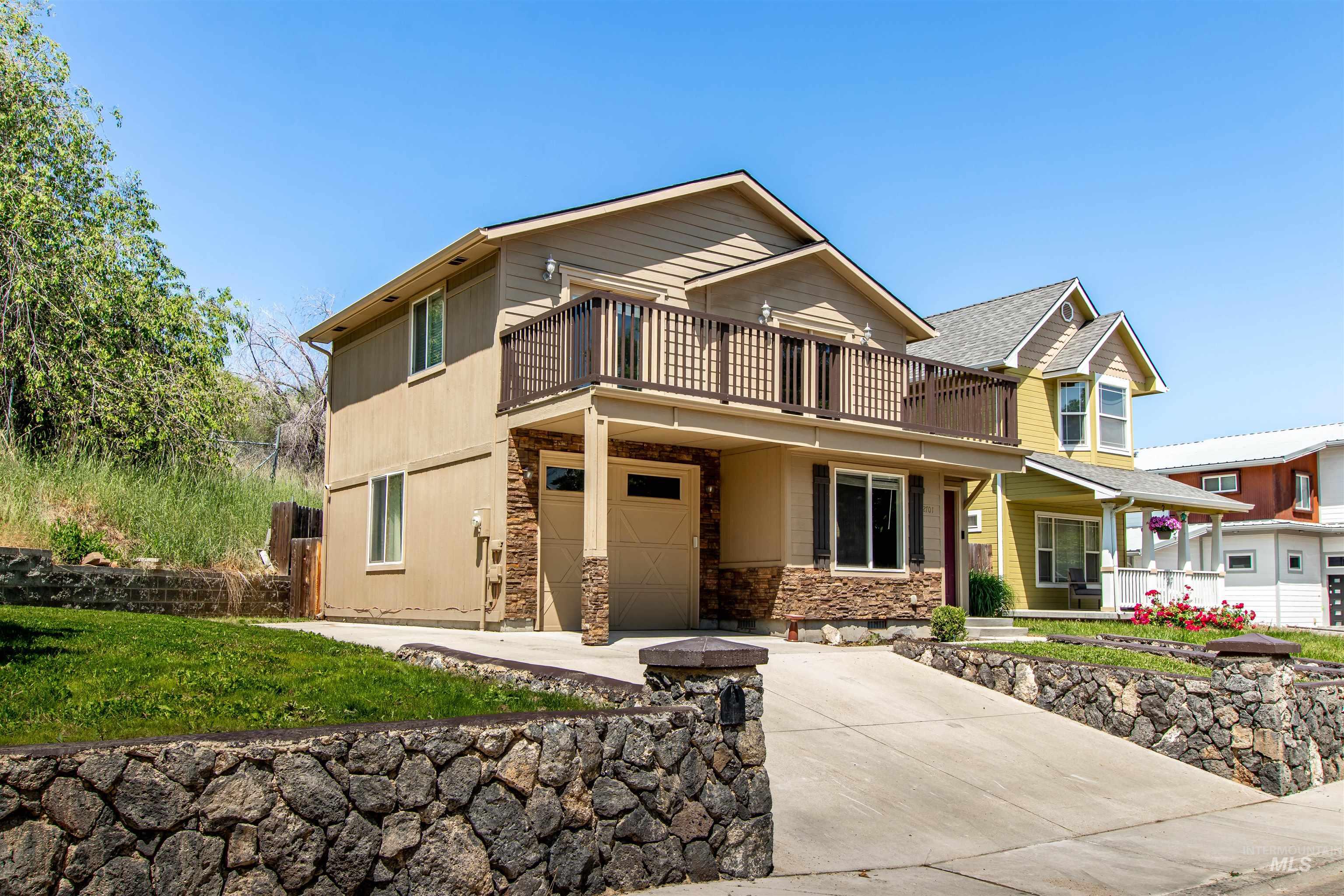View of front of property with concrete driveway, a garage, stone siding, a porch, and a front yard