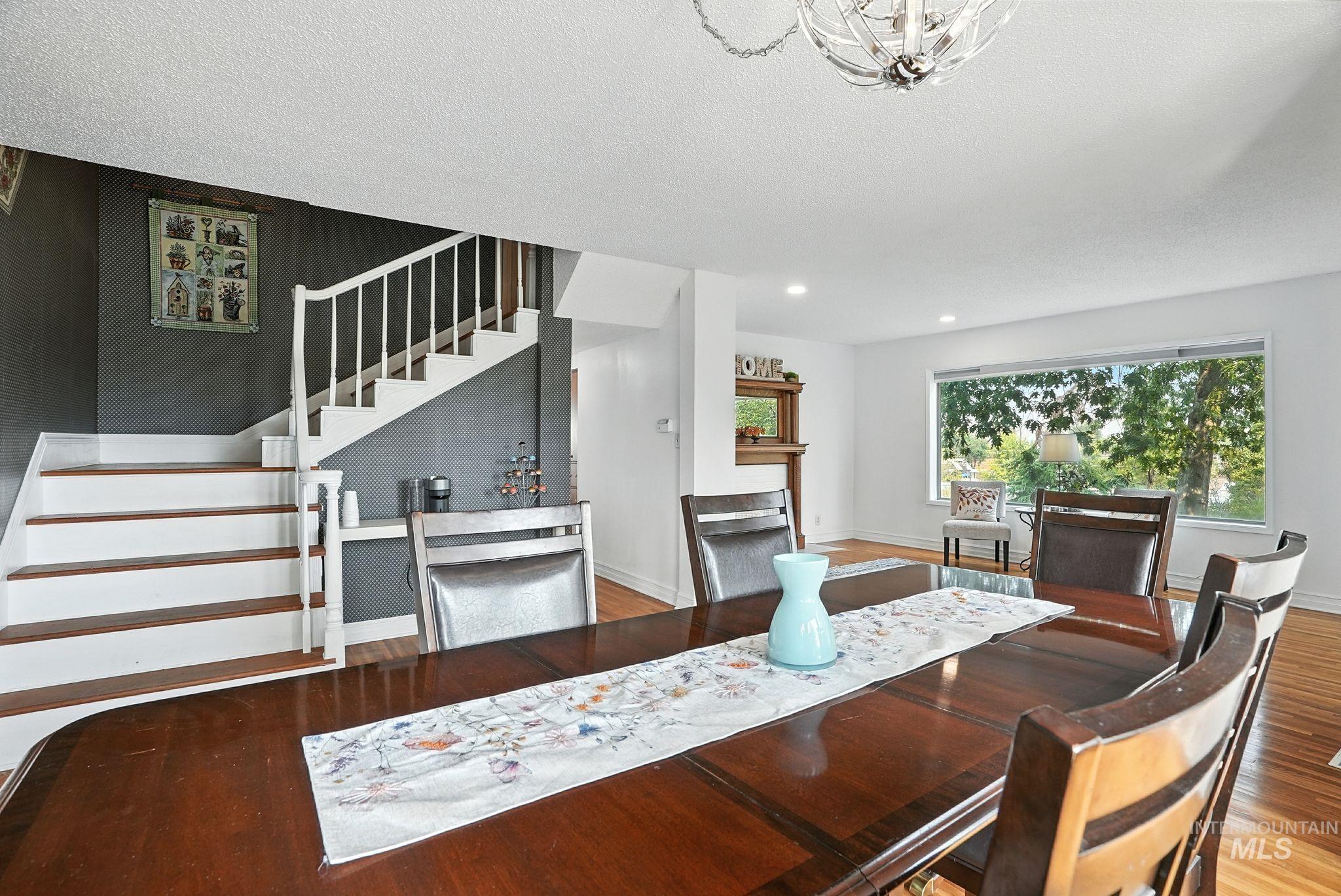 Dining space featuring stairway, wood finished floors, a textured ceiling, a chandelier, and recessed lighting