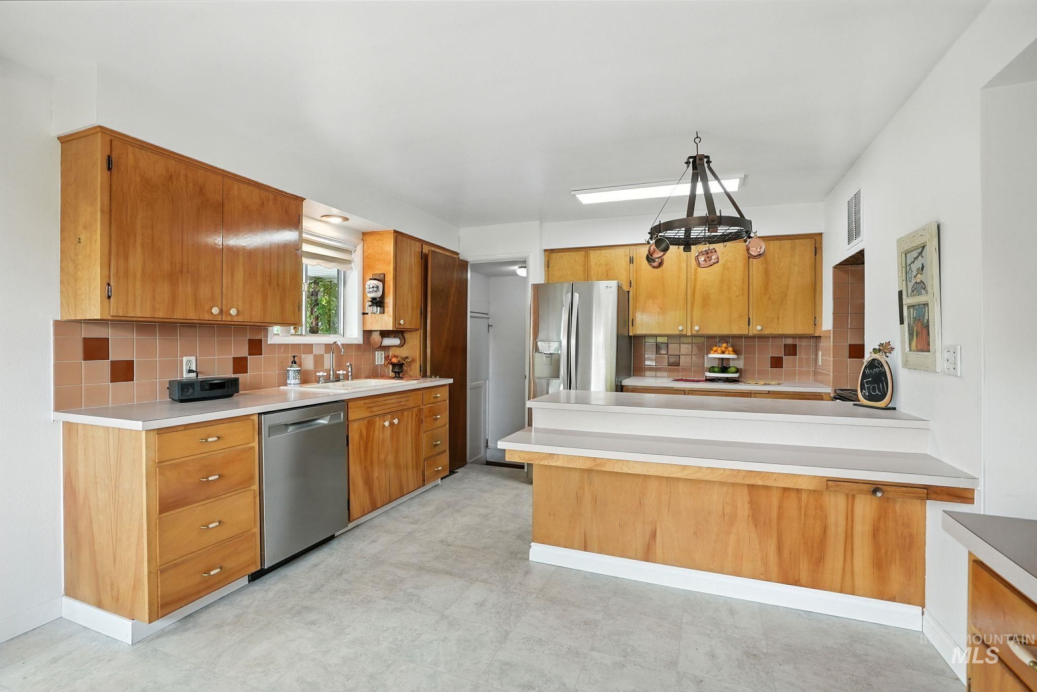 Kitchen with tasteful backsplash, a peninsula, and brown cabinetry
