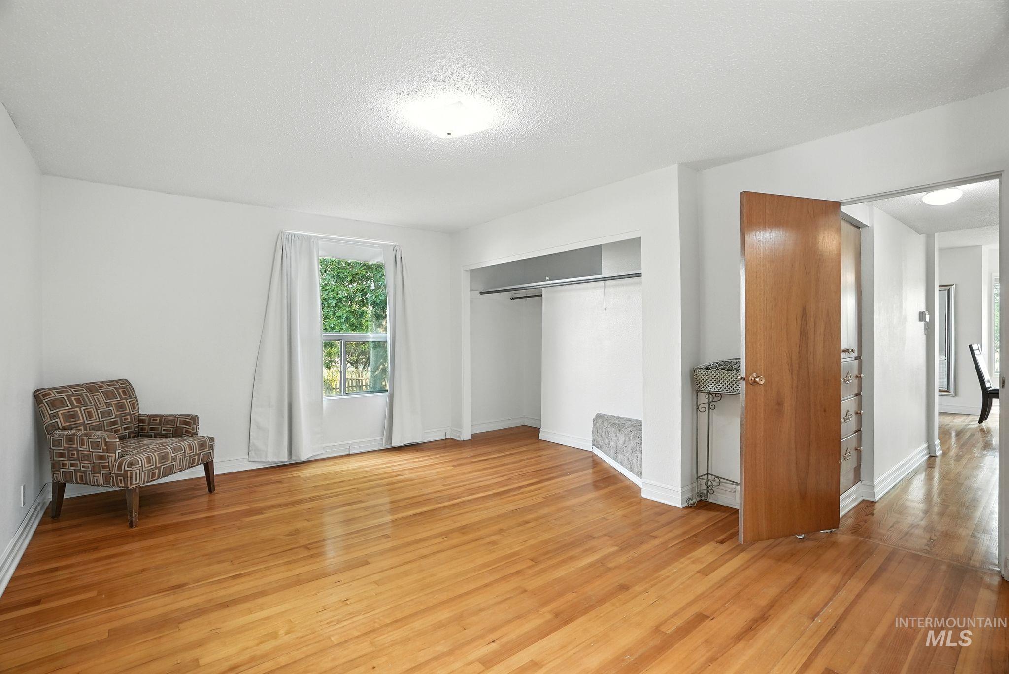 Unfurnished bedroom with light wood-style flooring, a textured ceiling, and a closet