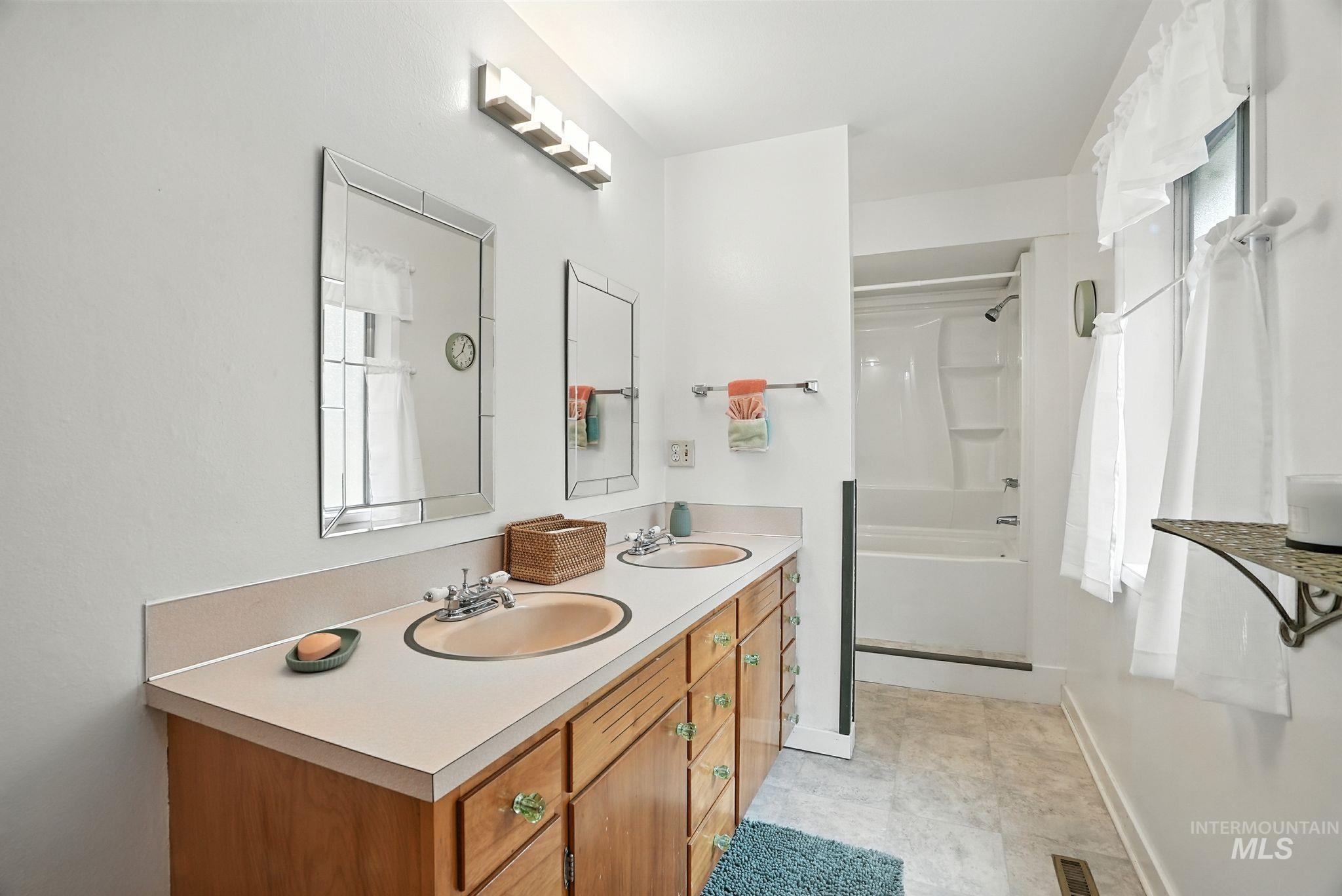 Bathroom with double vanity and bathtub / shower combination