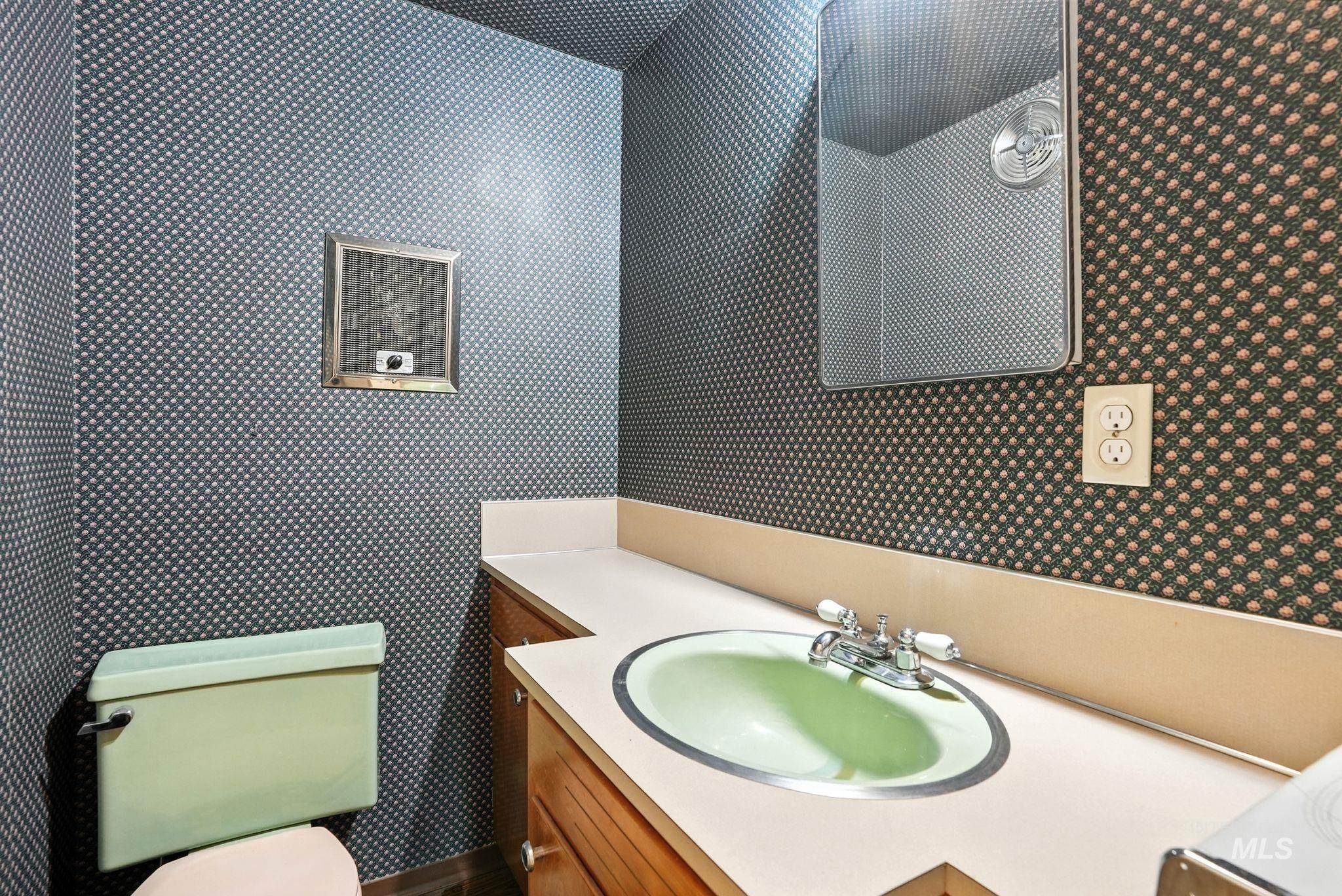 Half bath with vanity and wallpapered walls