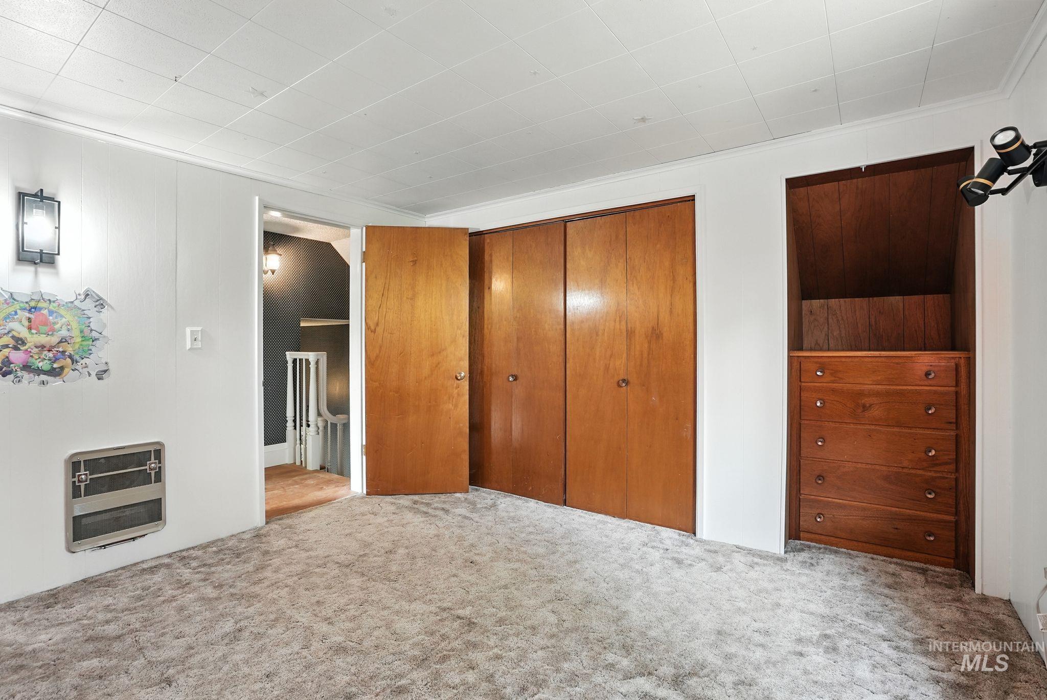 Unfurnished bedroom with carpet floors, a closet, and heating unit