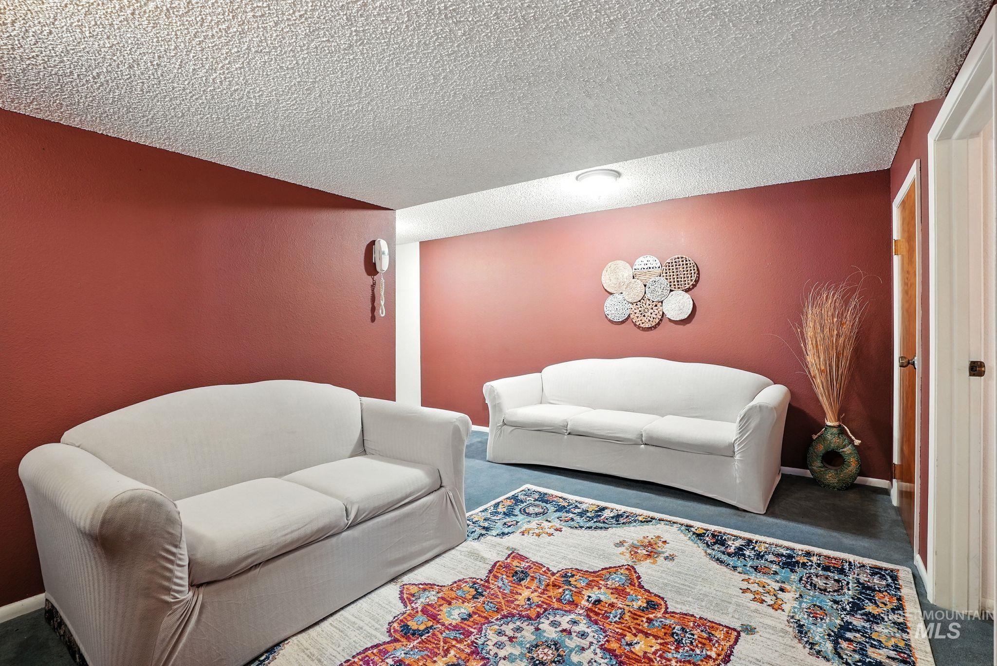 Carpeted living room with baseboards and a textured ceiling