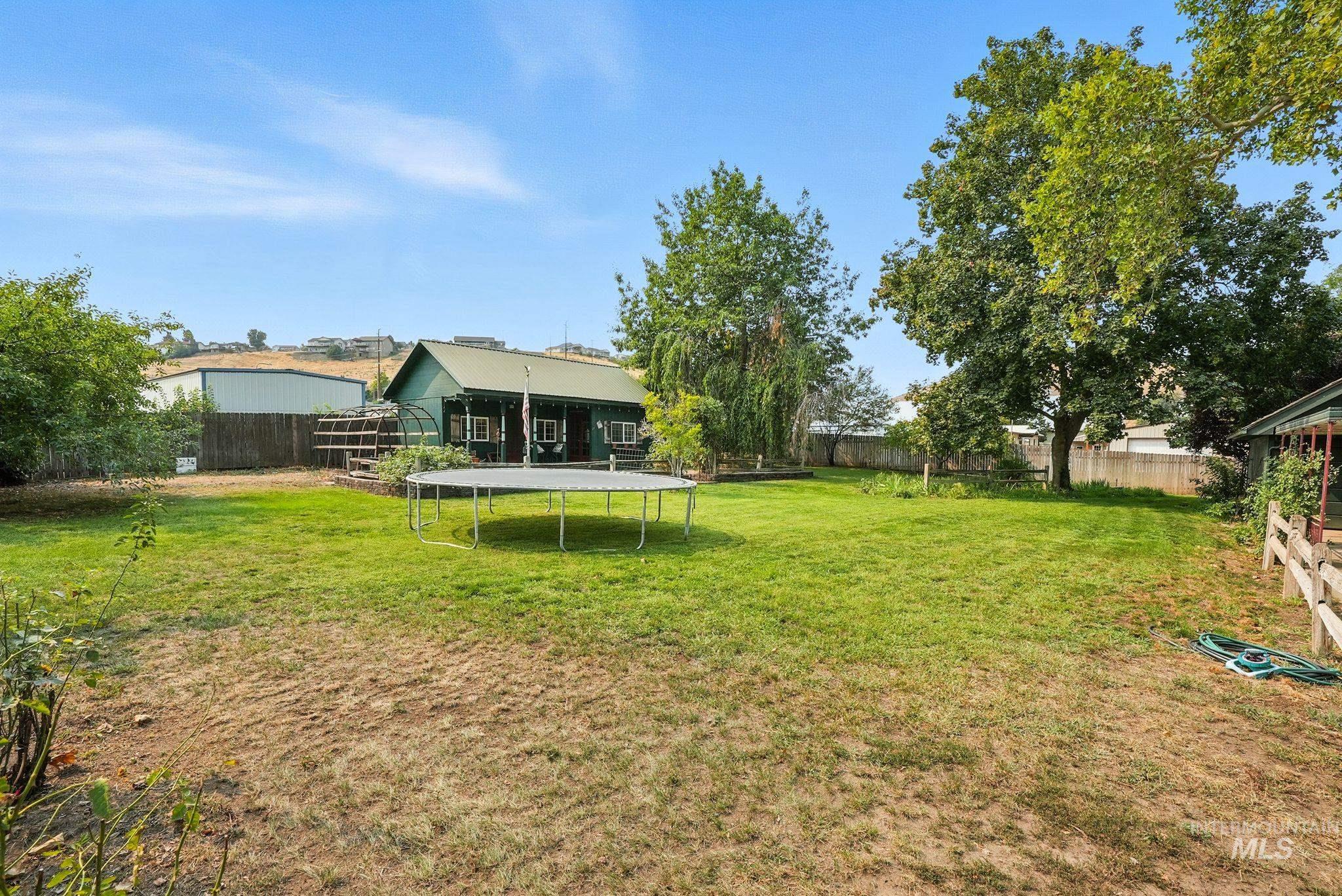 Fenced backyard featuring a trampoline and a patio