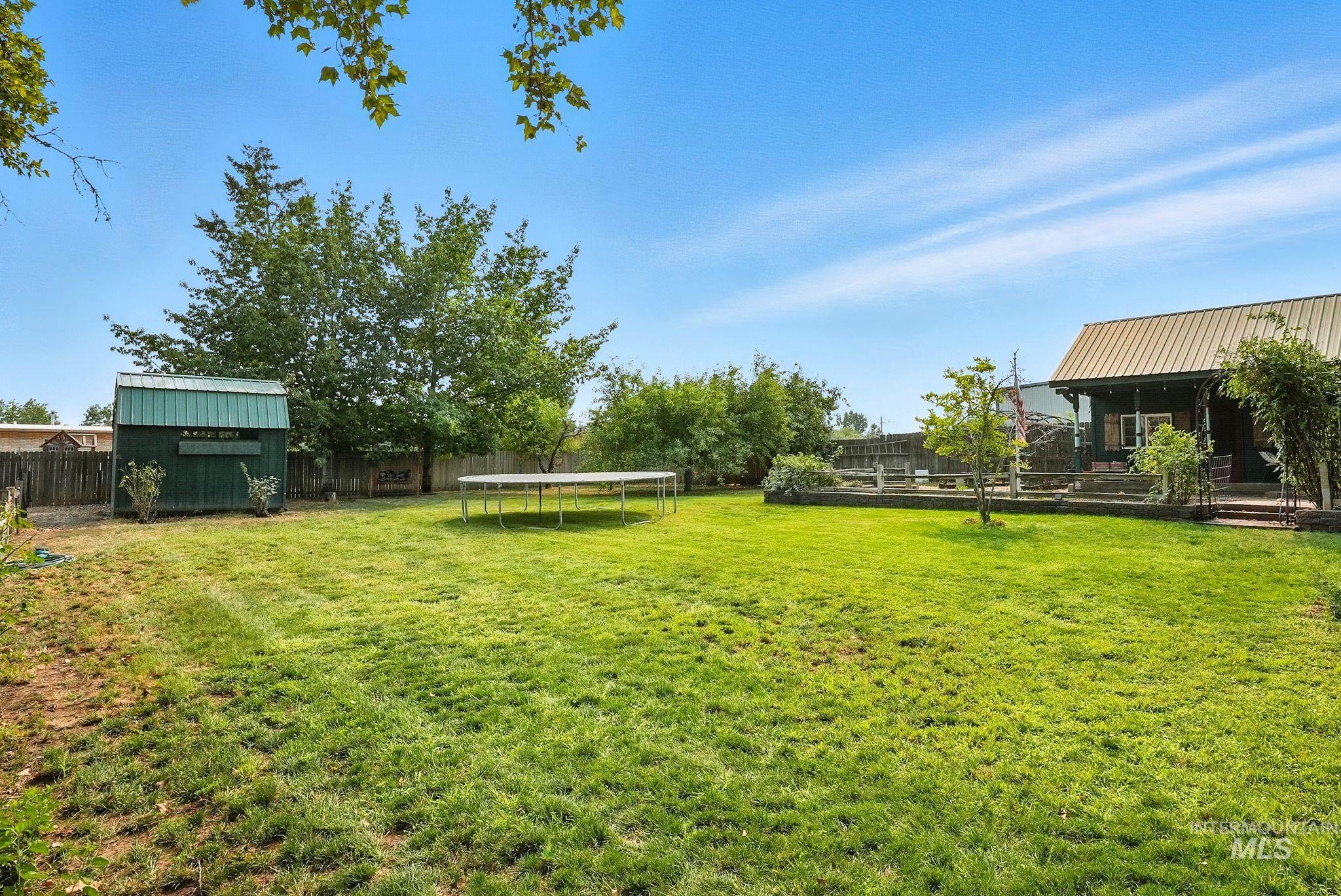 Fenced backyard with a trampoline and a storage unit