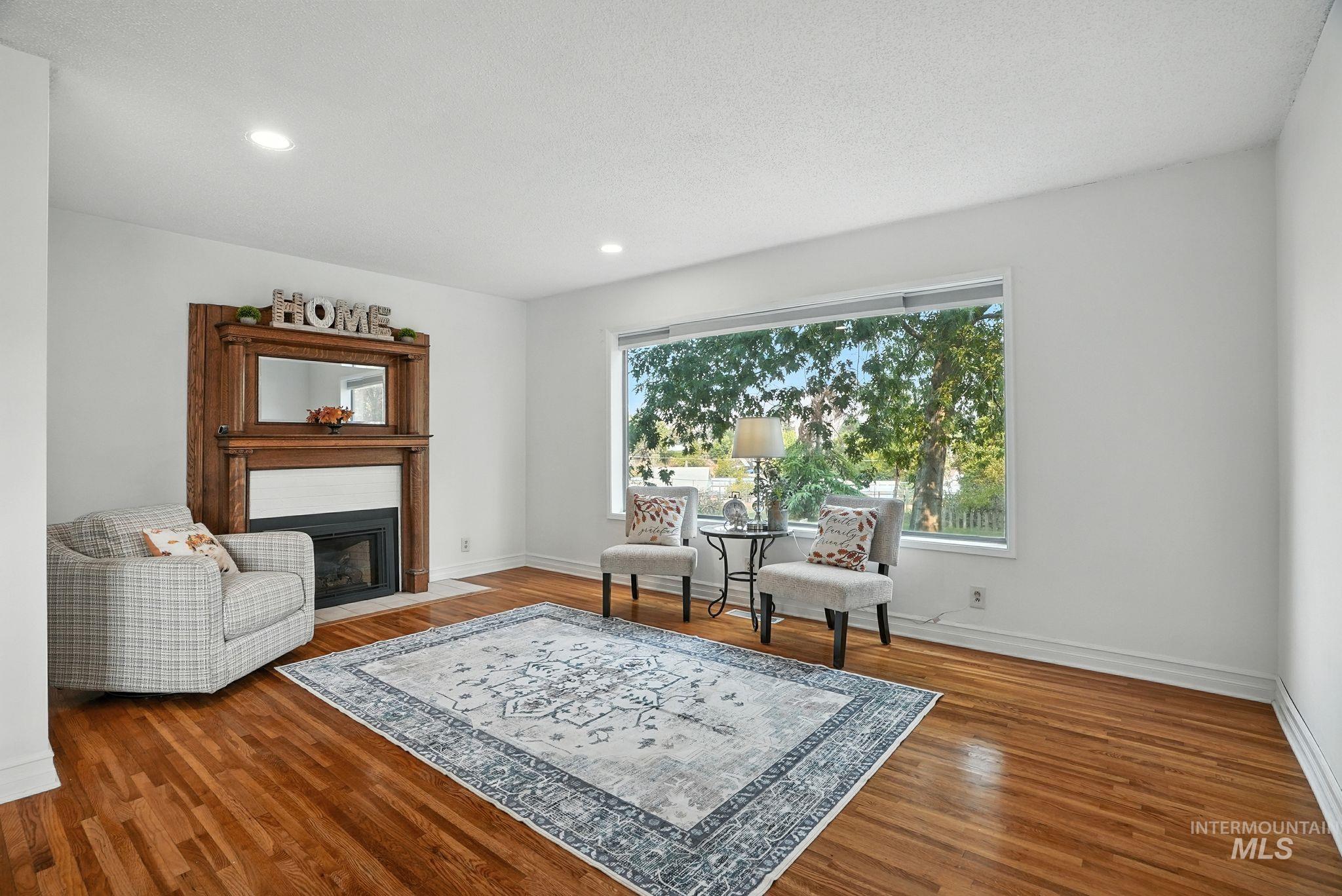 Sitting room featuring a fireplace with flush hearth, wood finished floors, and recessed lighting