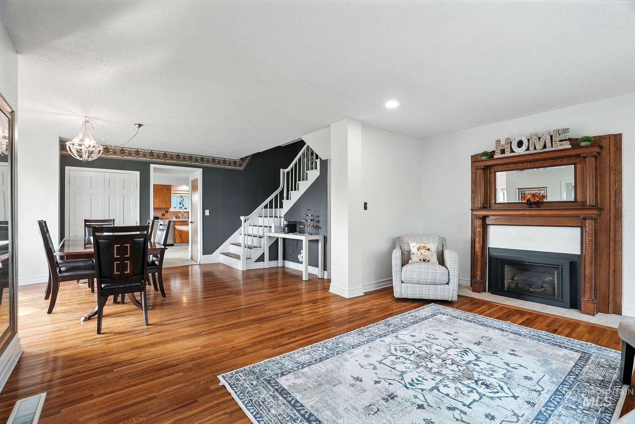 Living area with wood finished floors, a fireplace, stairway, recessed lighting, and a chandelier