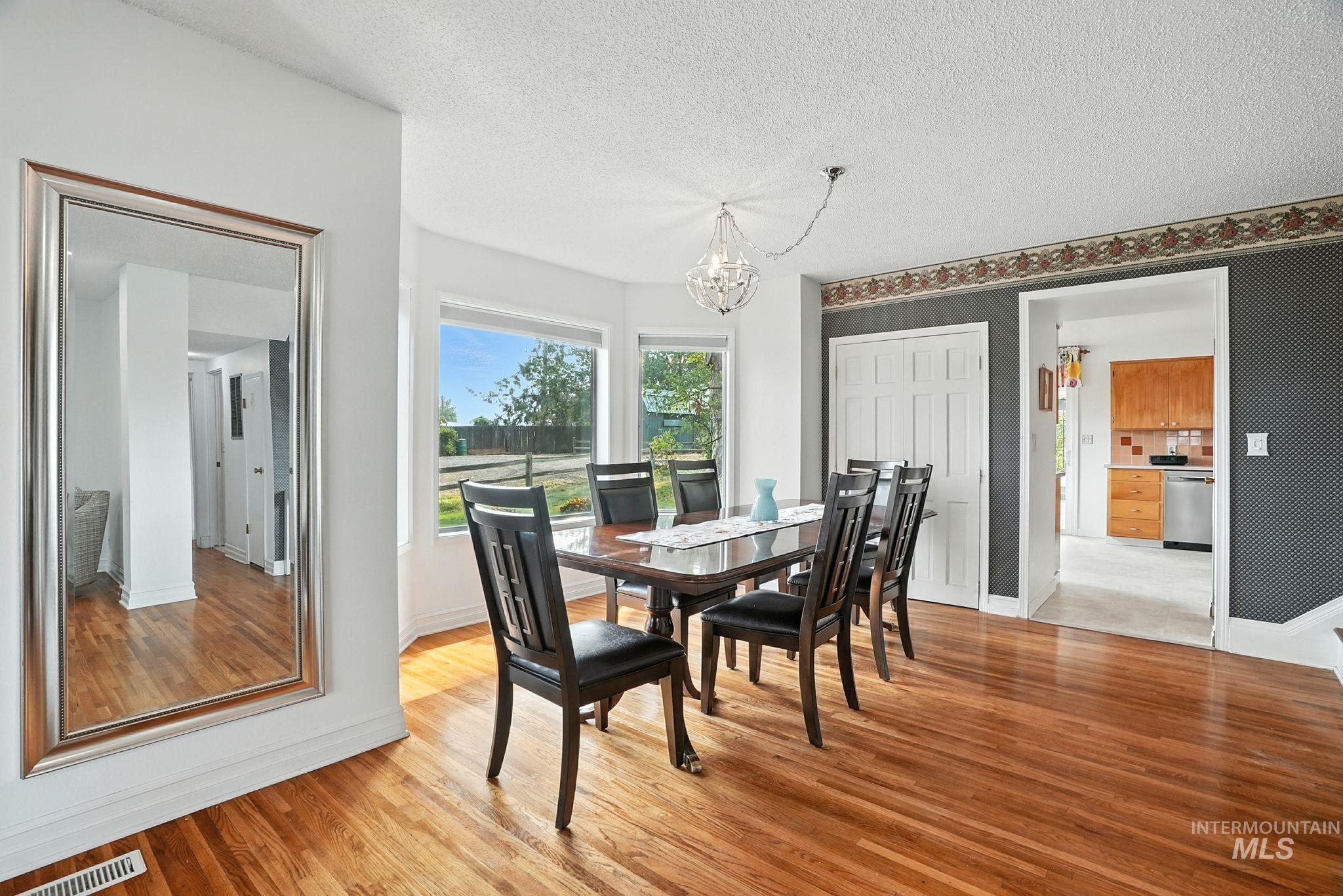 Dining room featuring light wood-style flooring, a textured ceiling, and a chandelier