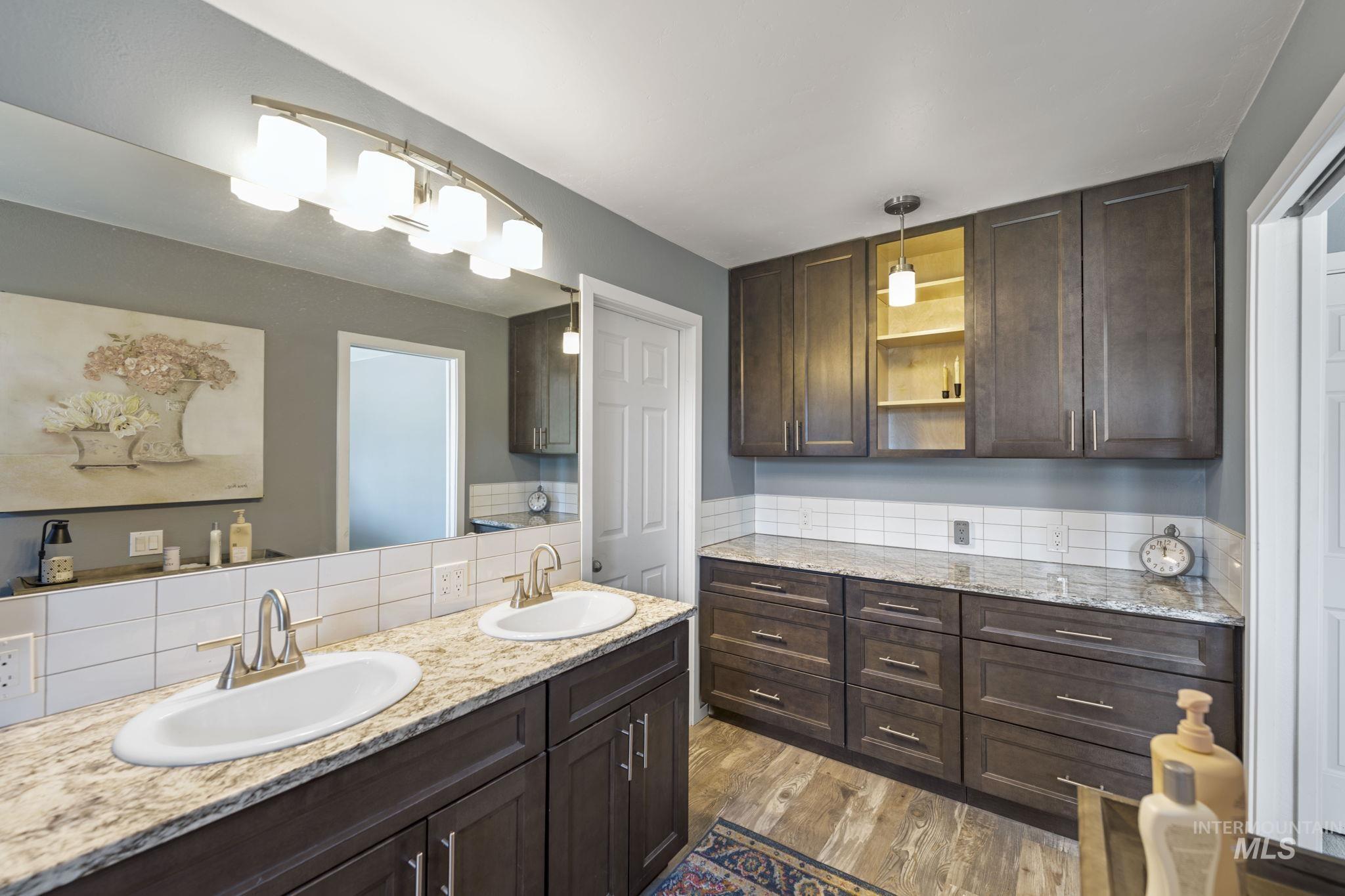 Bathroom featuring double vanity, light wood-style flooring, and backsplash