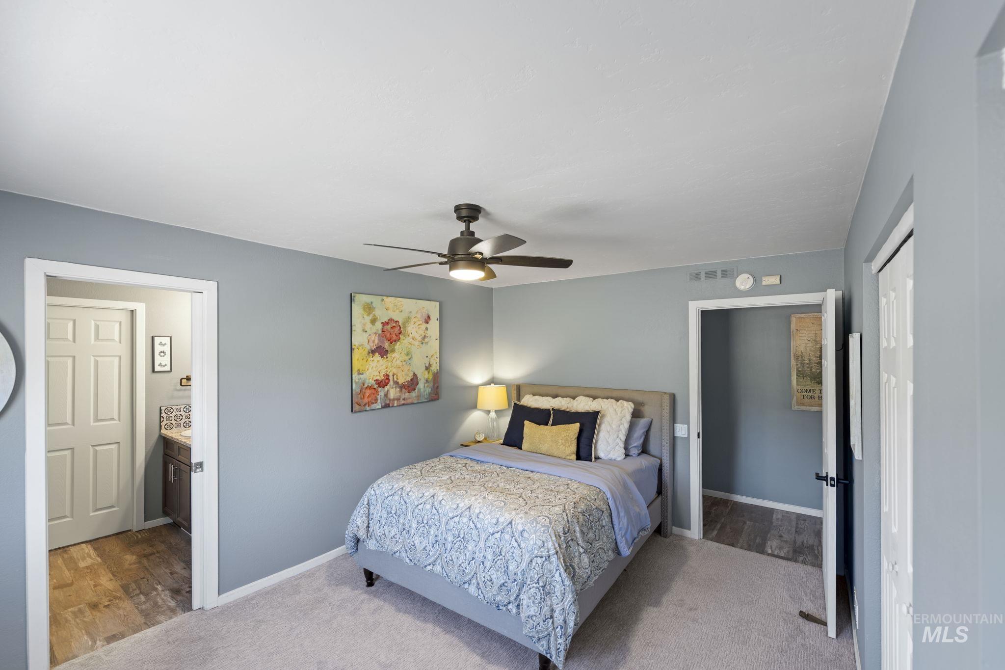 Carpeted bedroom featuring a closet, ceiling fan, wood finished floors, and connected bathroom