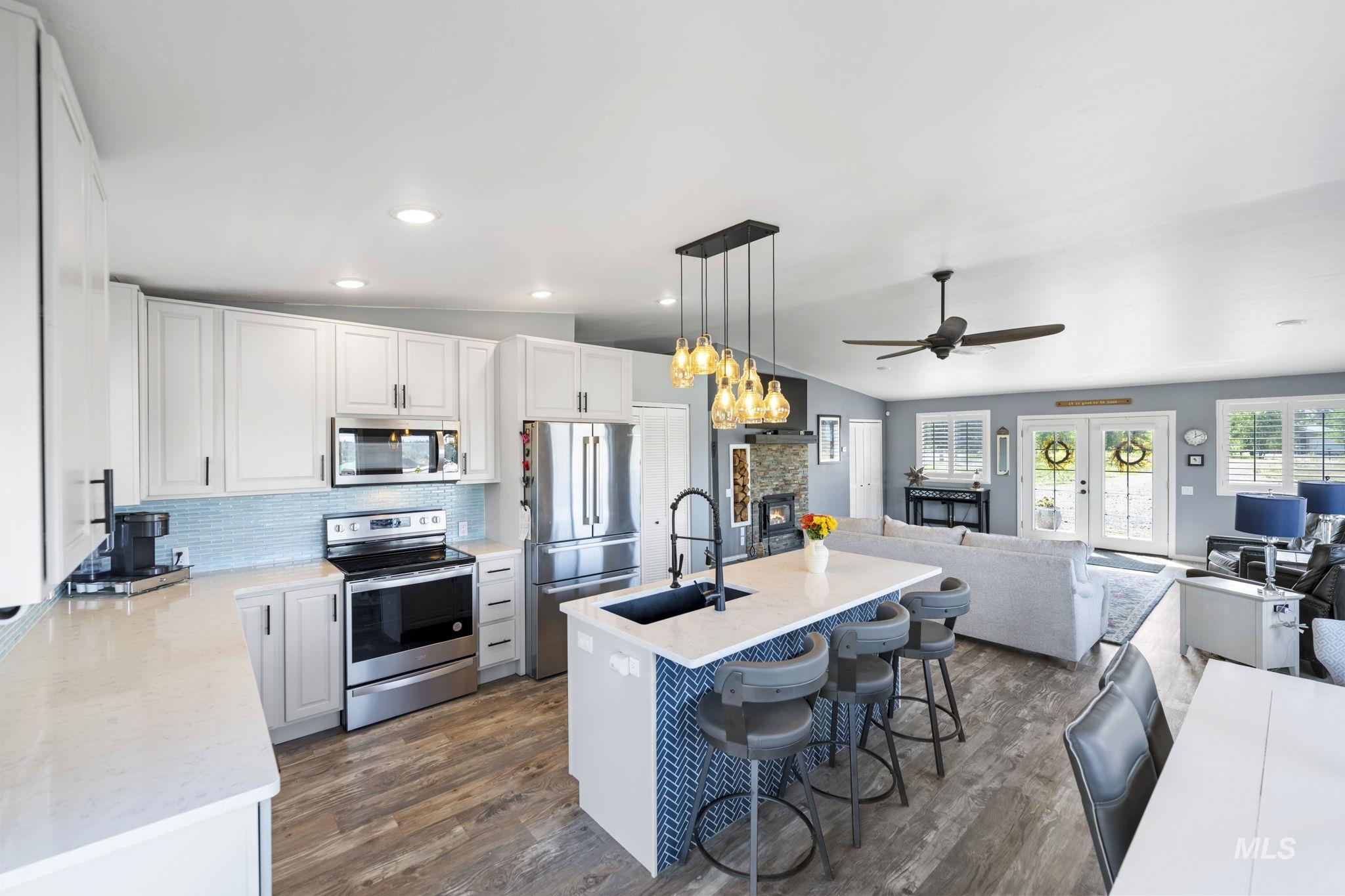 Kitchen with a breakfast bar area, appliances with stainless steel finishes, vaulted ceiling, decorative backsplash, and open floor plan