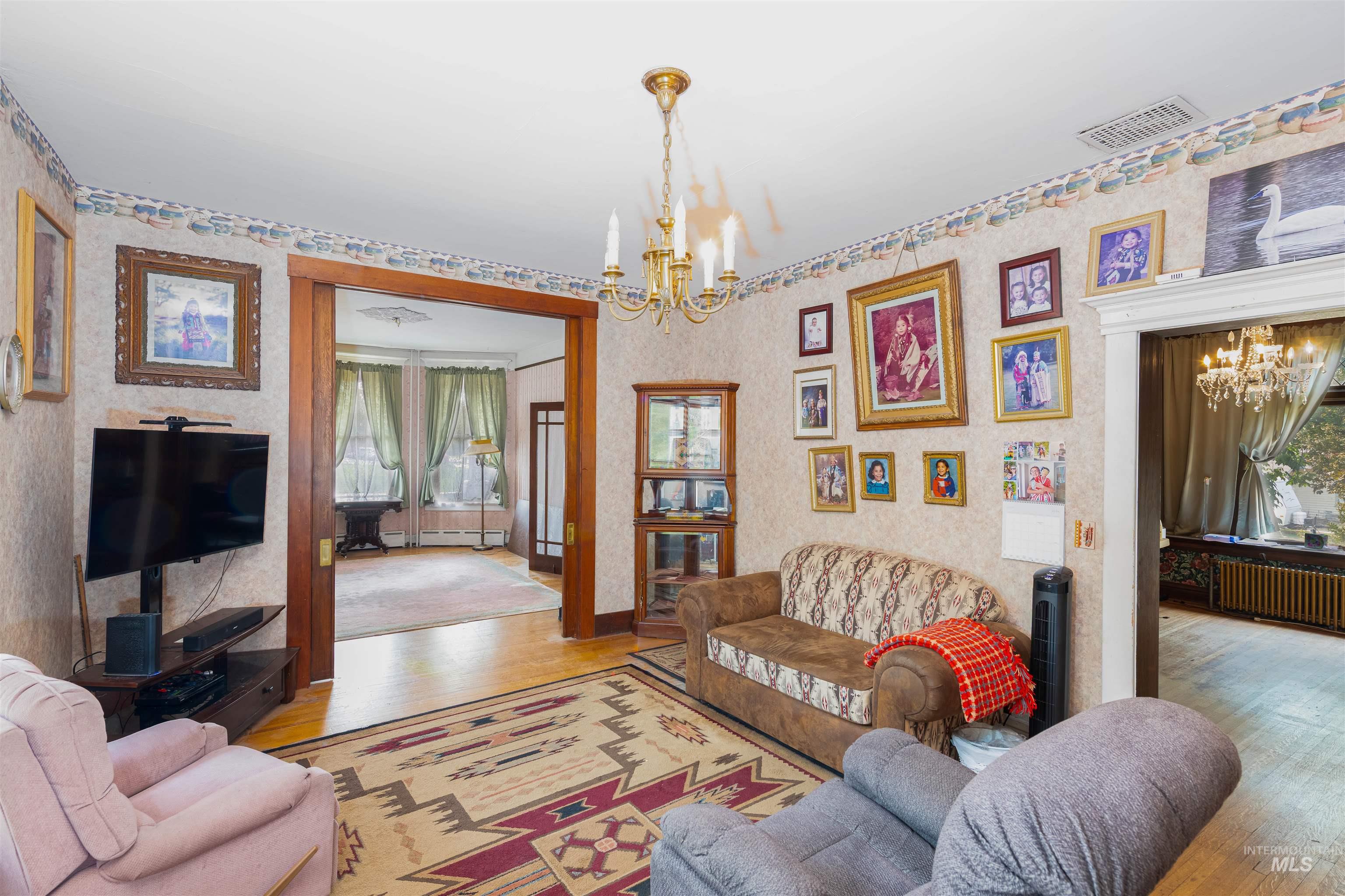 Living area featuring a chandelier, wood finished floors, radiator heating unit, and a baseboard heating unit