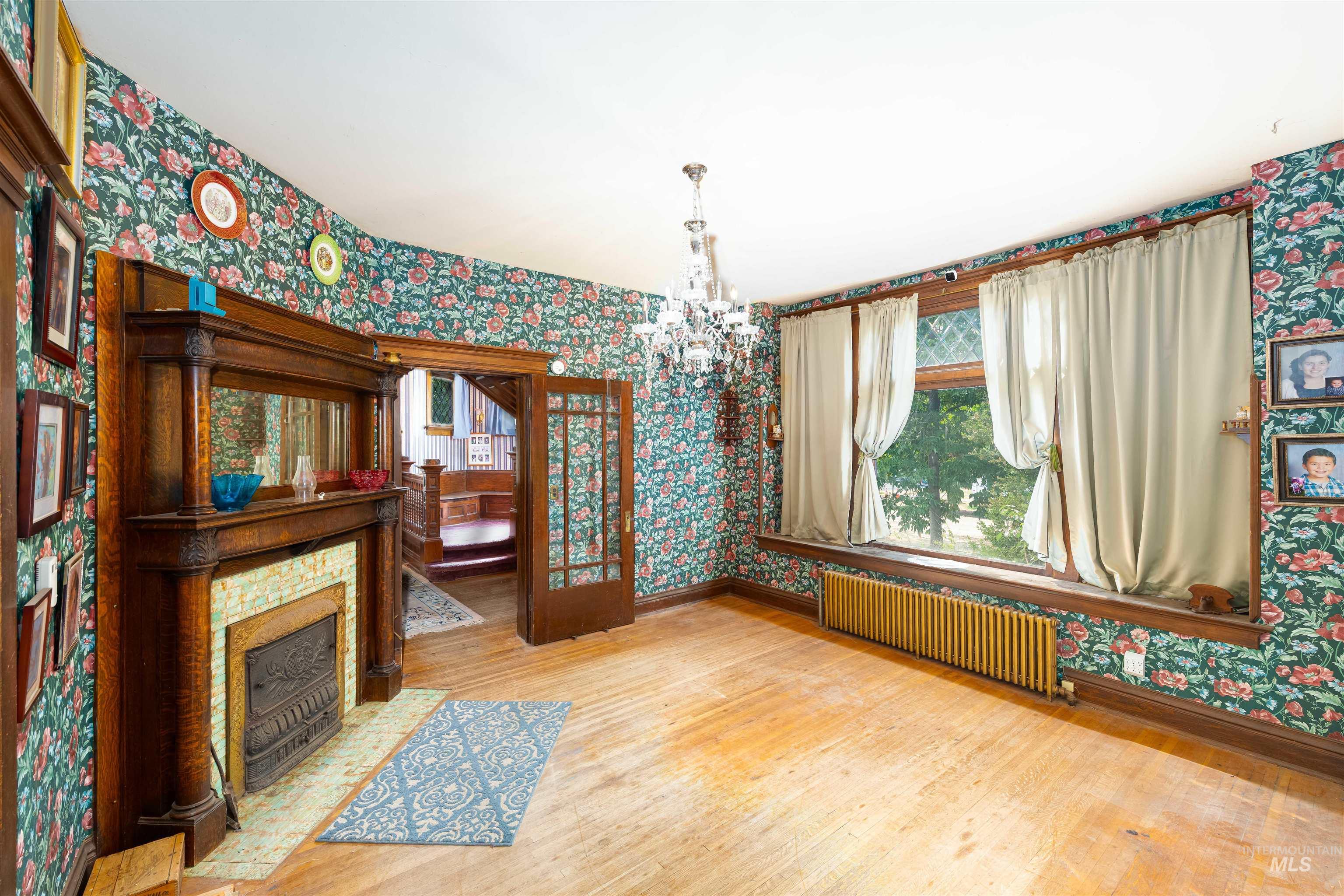 Unfurnished dining area featuring wallpapered walls, light wood-style floors, radiator, and a chandelier