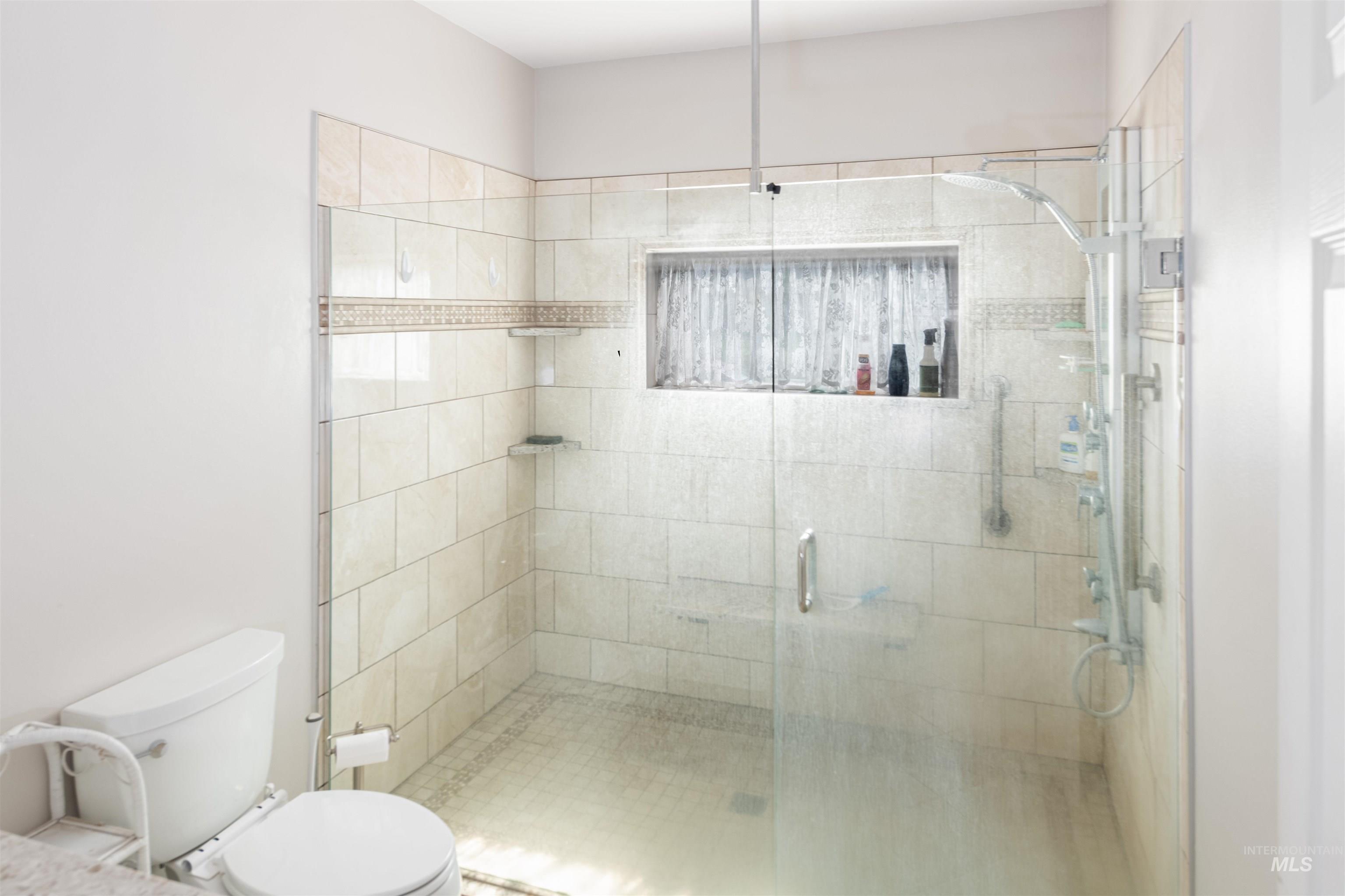 Full bathroom featuring toilet and a shower stall
