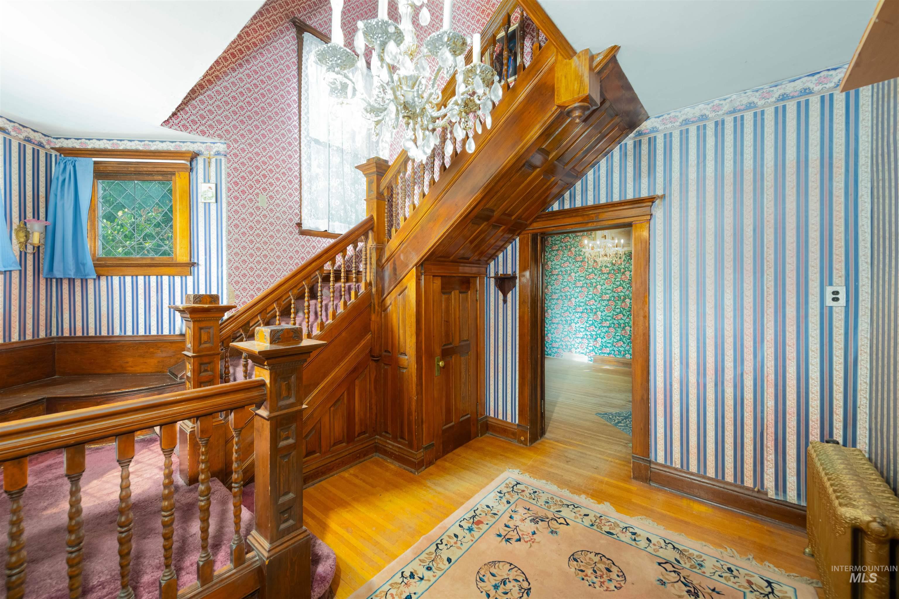 Staircase with wallpapered walls and wood finished floors