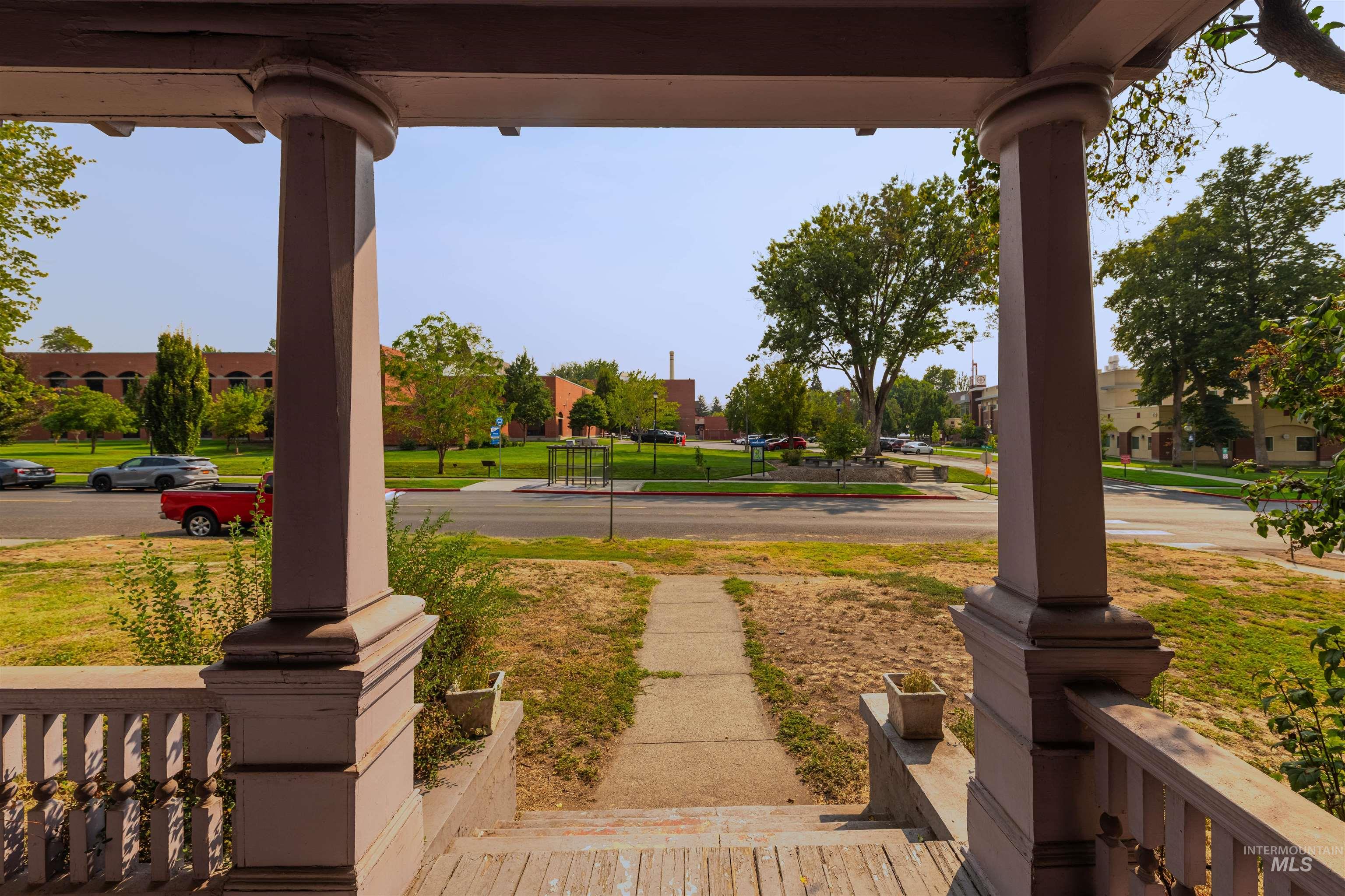 View of grassy yard featuring covered porch and a residential view