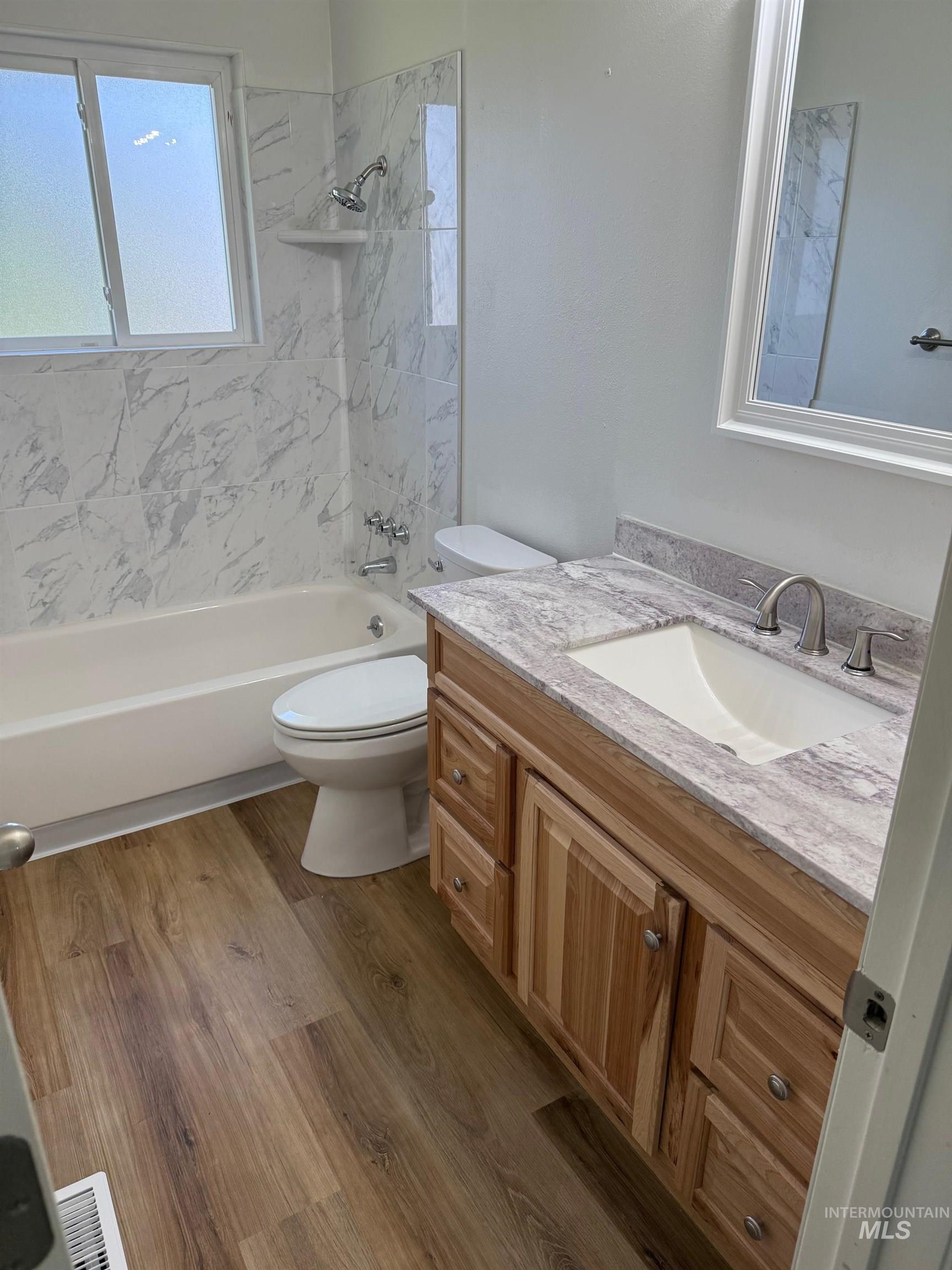 Bathroom featuring vanity, washtub / shower combination, and dark wood finished floors