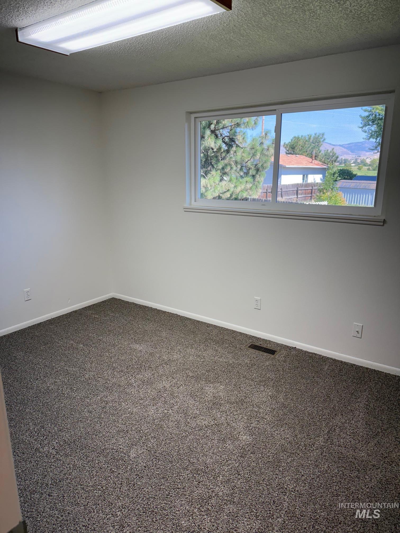Empty room with dark carpet and a textured ceiling