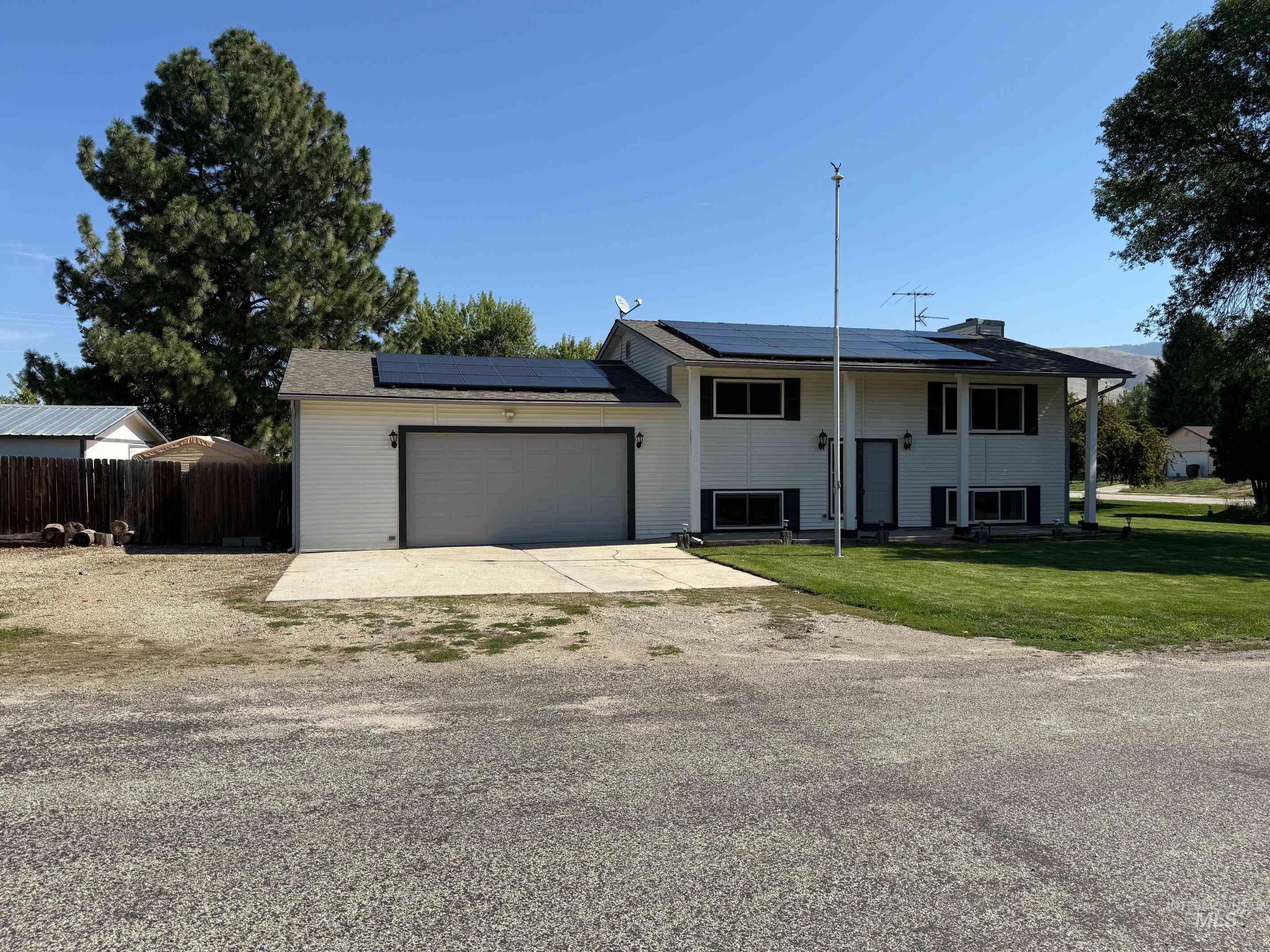 Split foyer home with solar panels, driveway, a garage, and covered porch