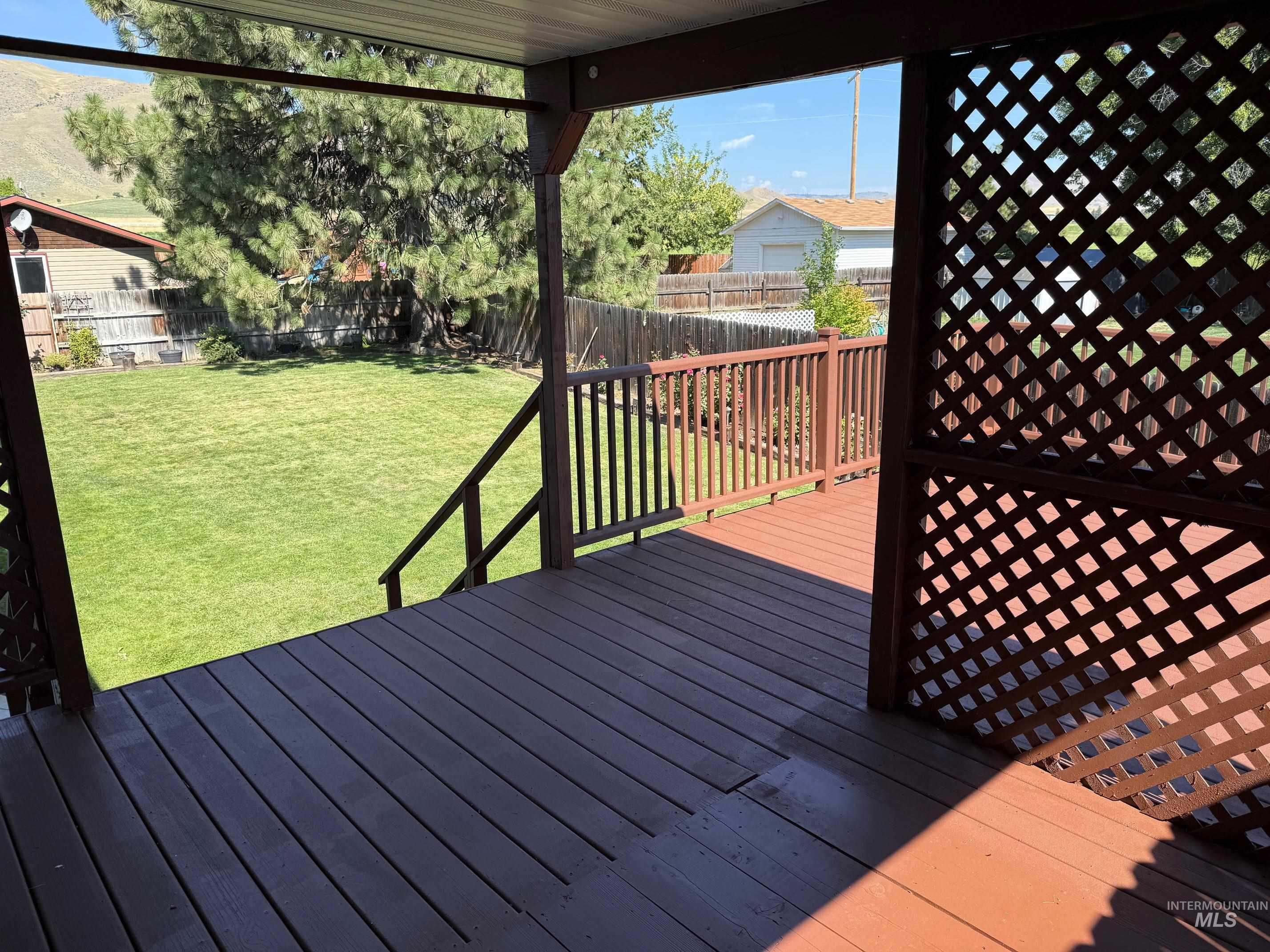 Wooden terrace with a fenced backyard
