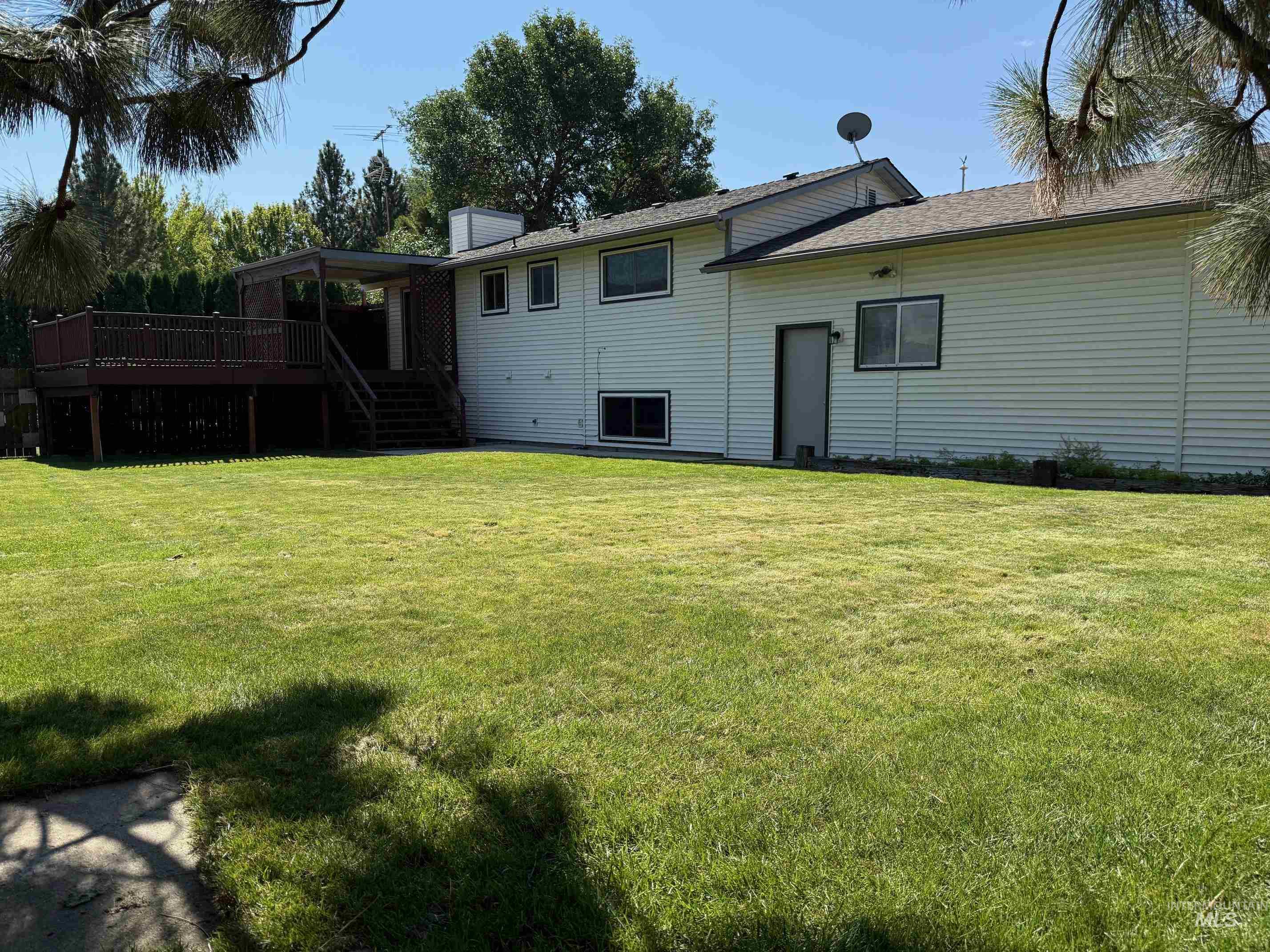 Back of property with stairway, a yard, a chimney, and a deck